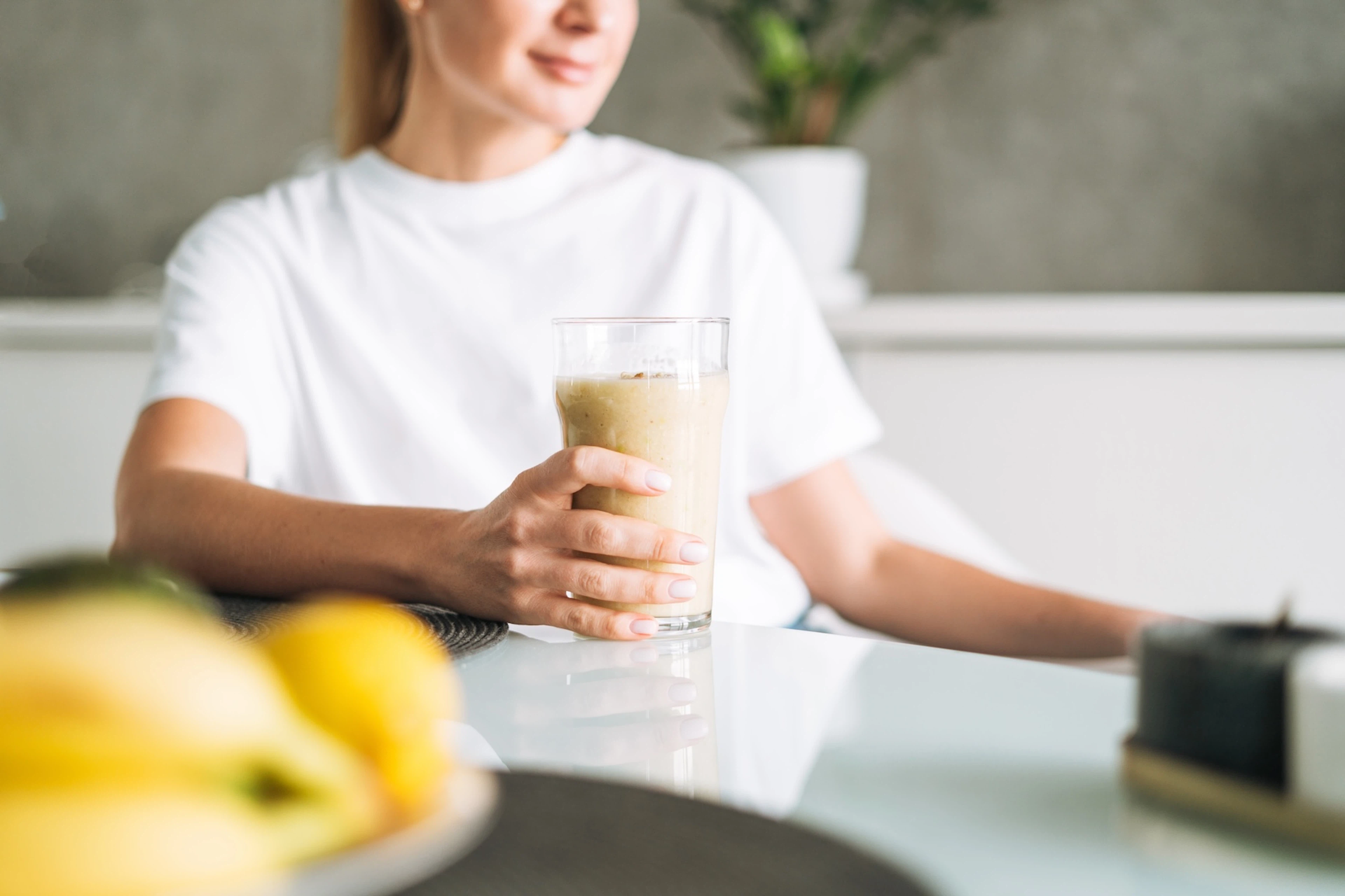 A woman sipping a smoothie at home to help her carb load before her race.