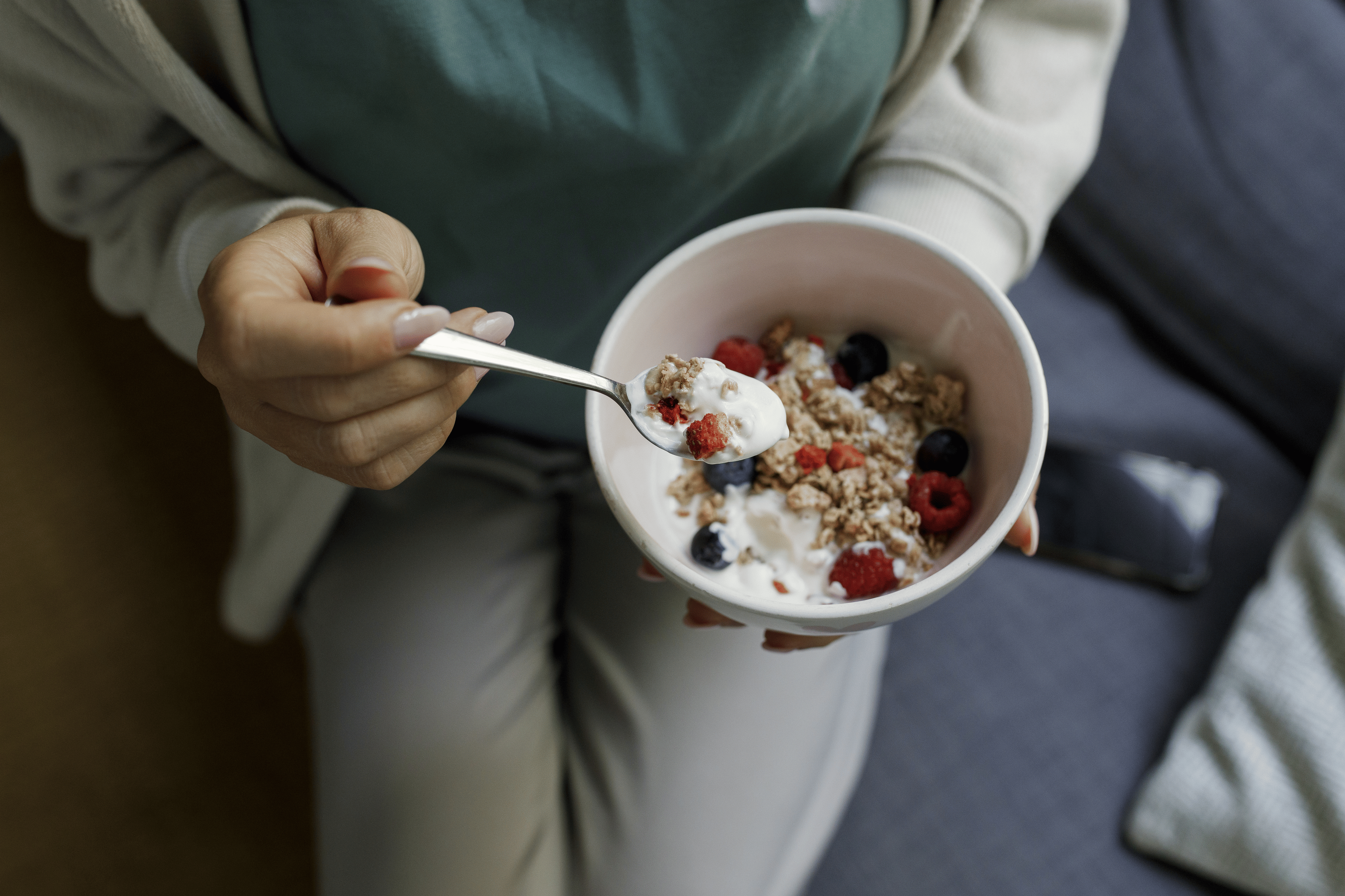 A person eating a Greek yogurt parfait as a healthy late-night snack,