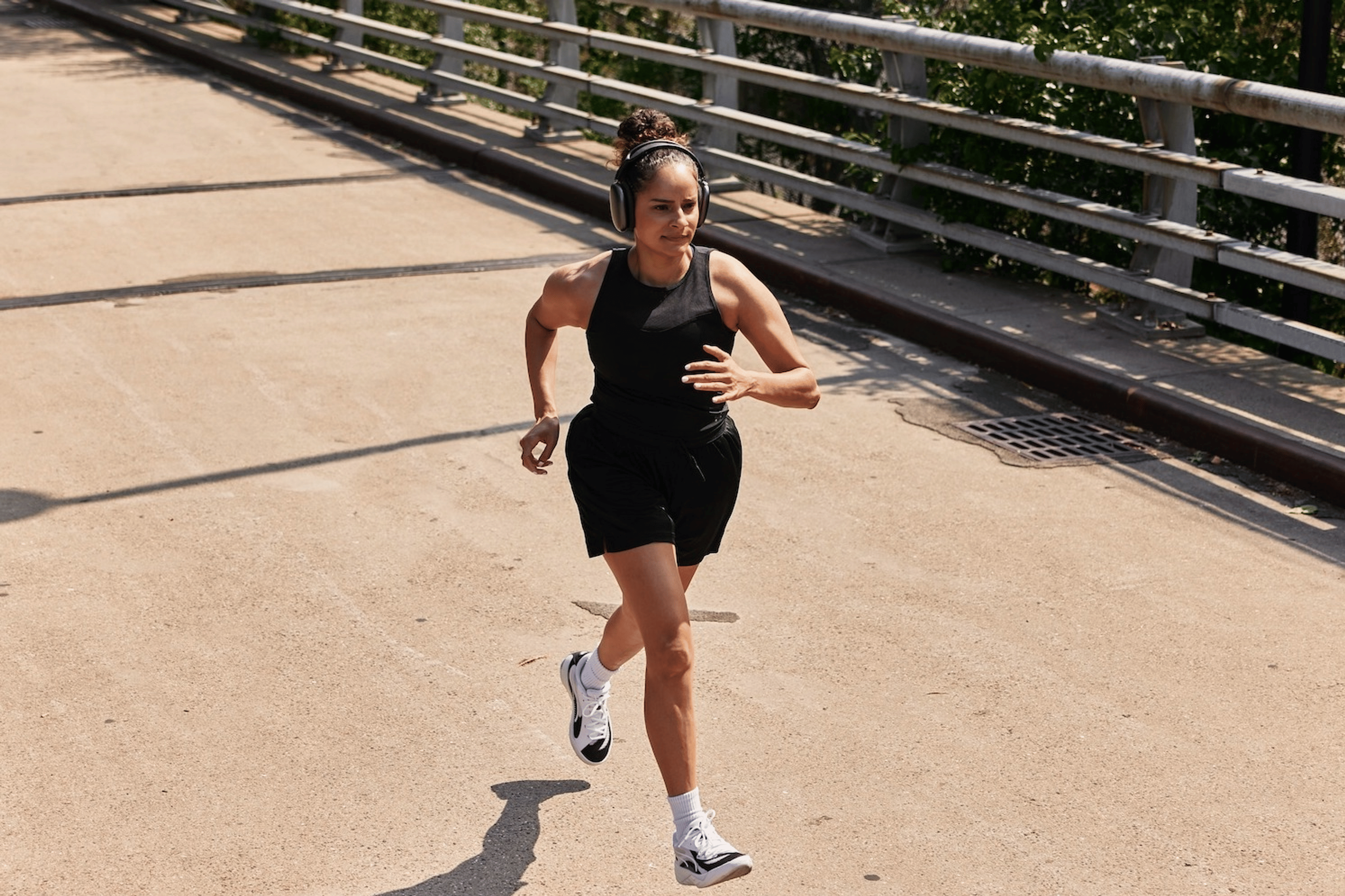 A woman running on an outdoor bridge on a sunny day.