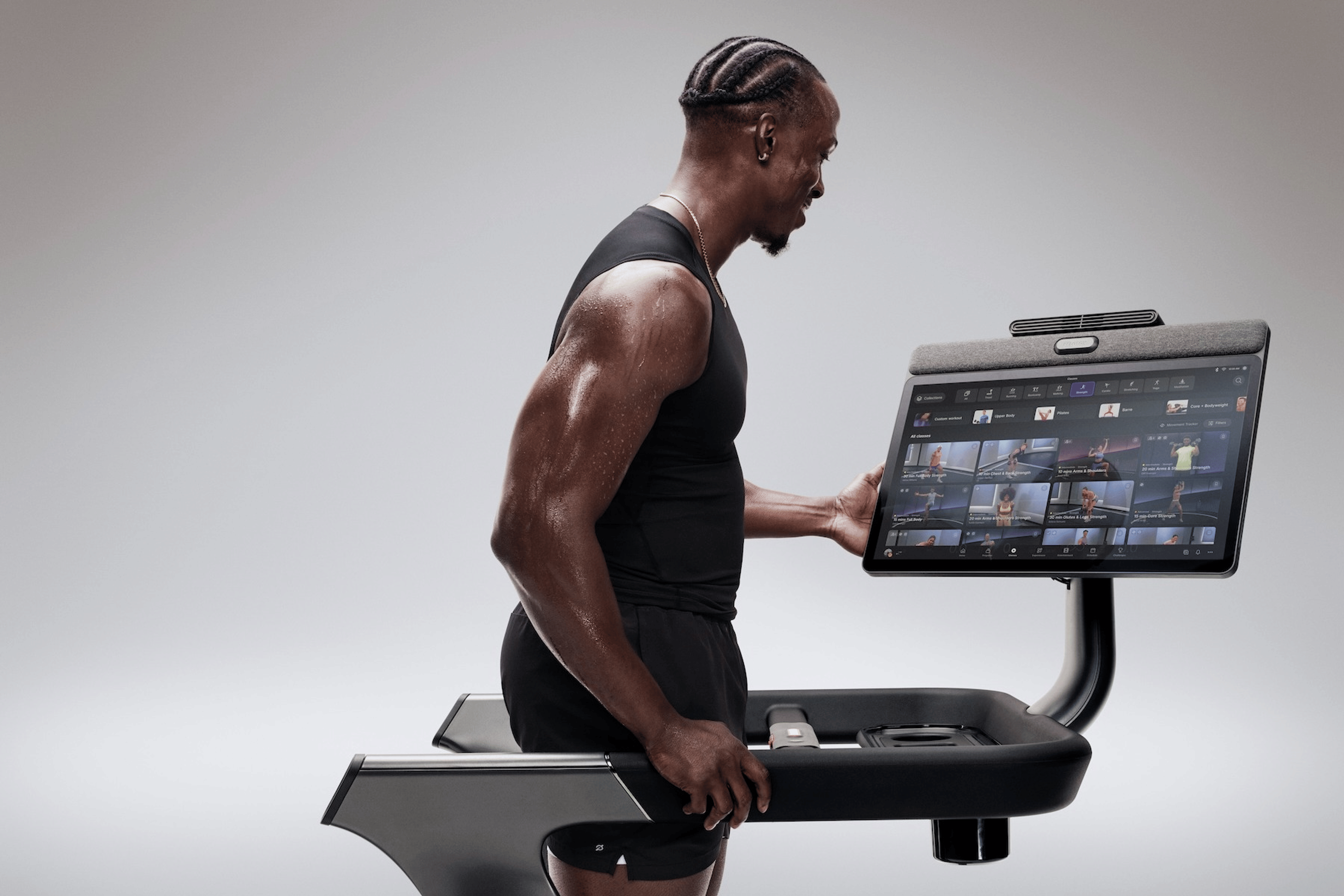 A woman doing a Peloton strength workout with dumbbells on the Peloton Cross Training Series Bike+ Powered by Peloton IQ.