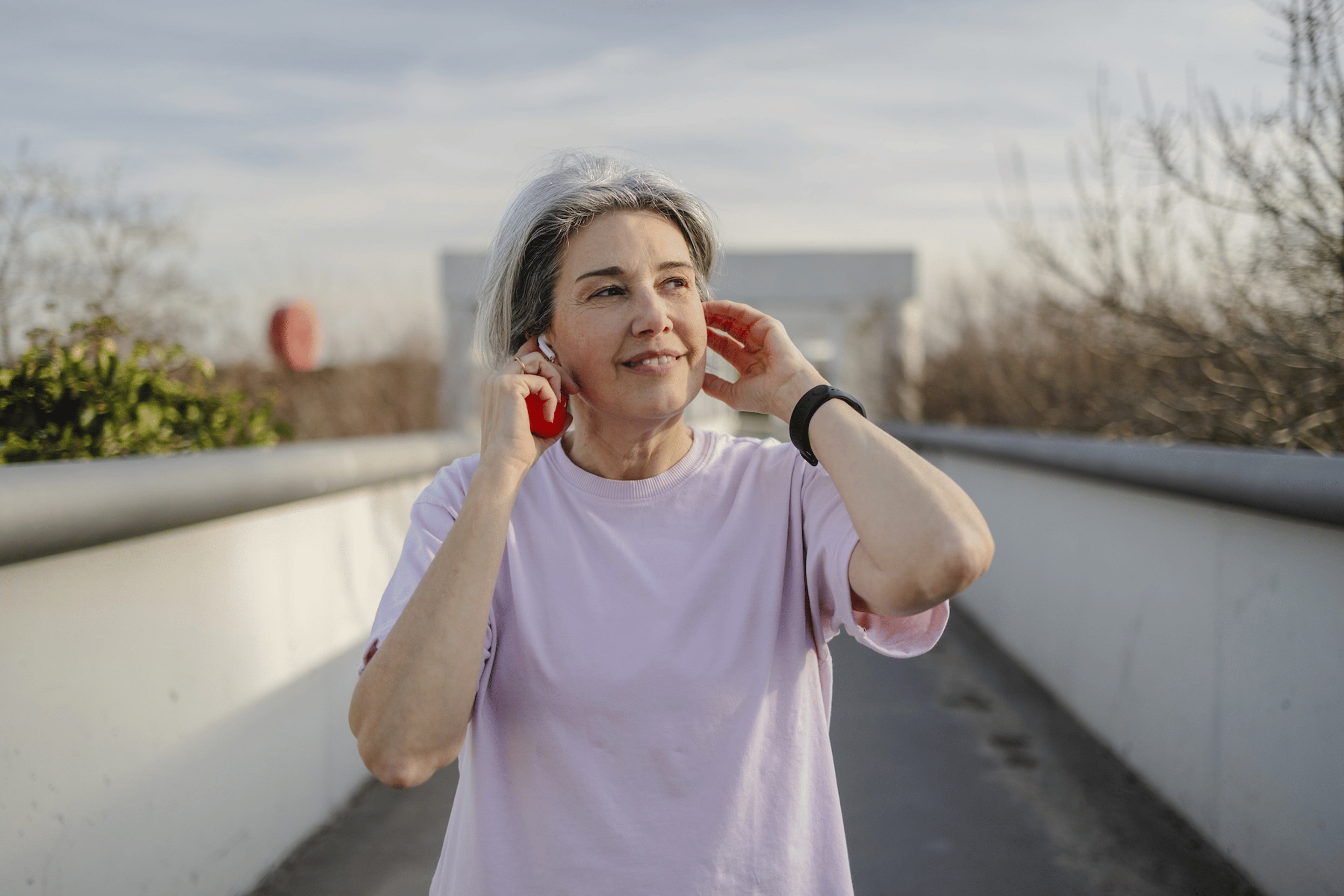 A woman walking outside and listening to music on a warm day. She is exercising to help ease arthritis symptoms.