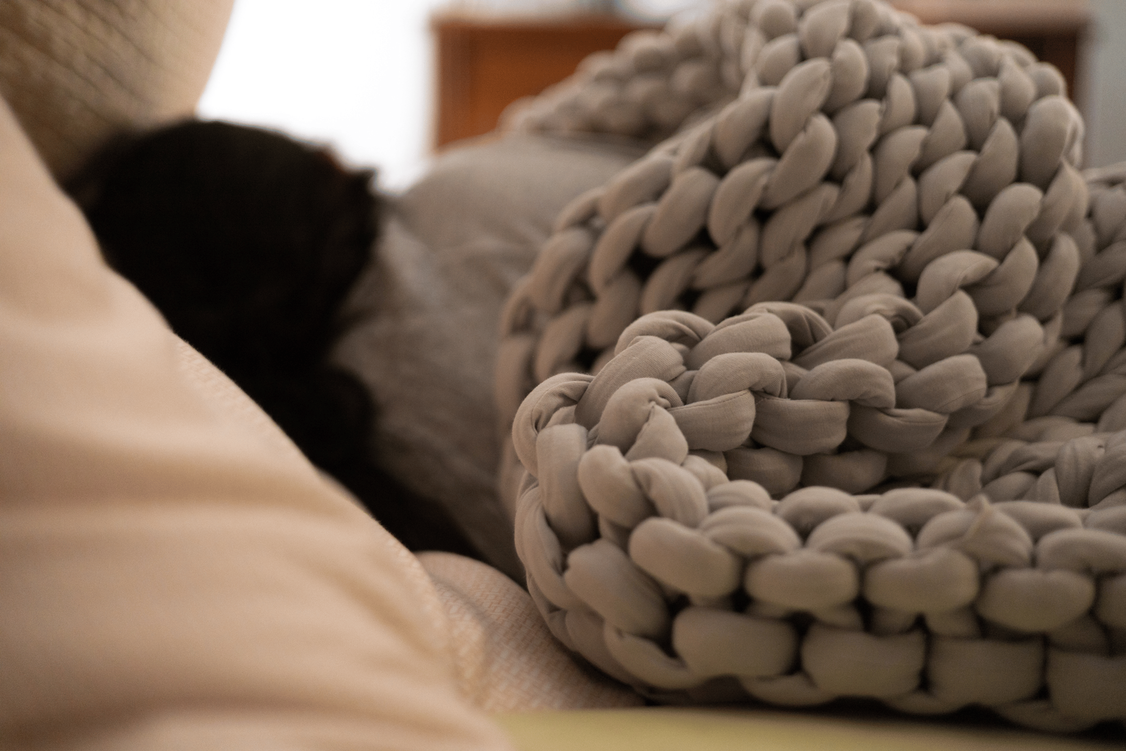 A woman sleeping peacefully under a braided weighted blanket. Weighted blankets offer many benefits.