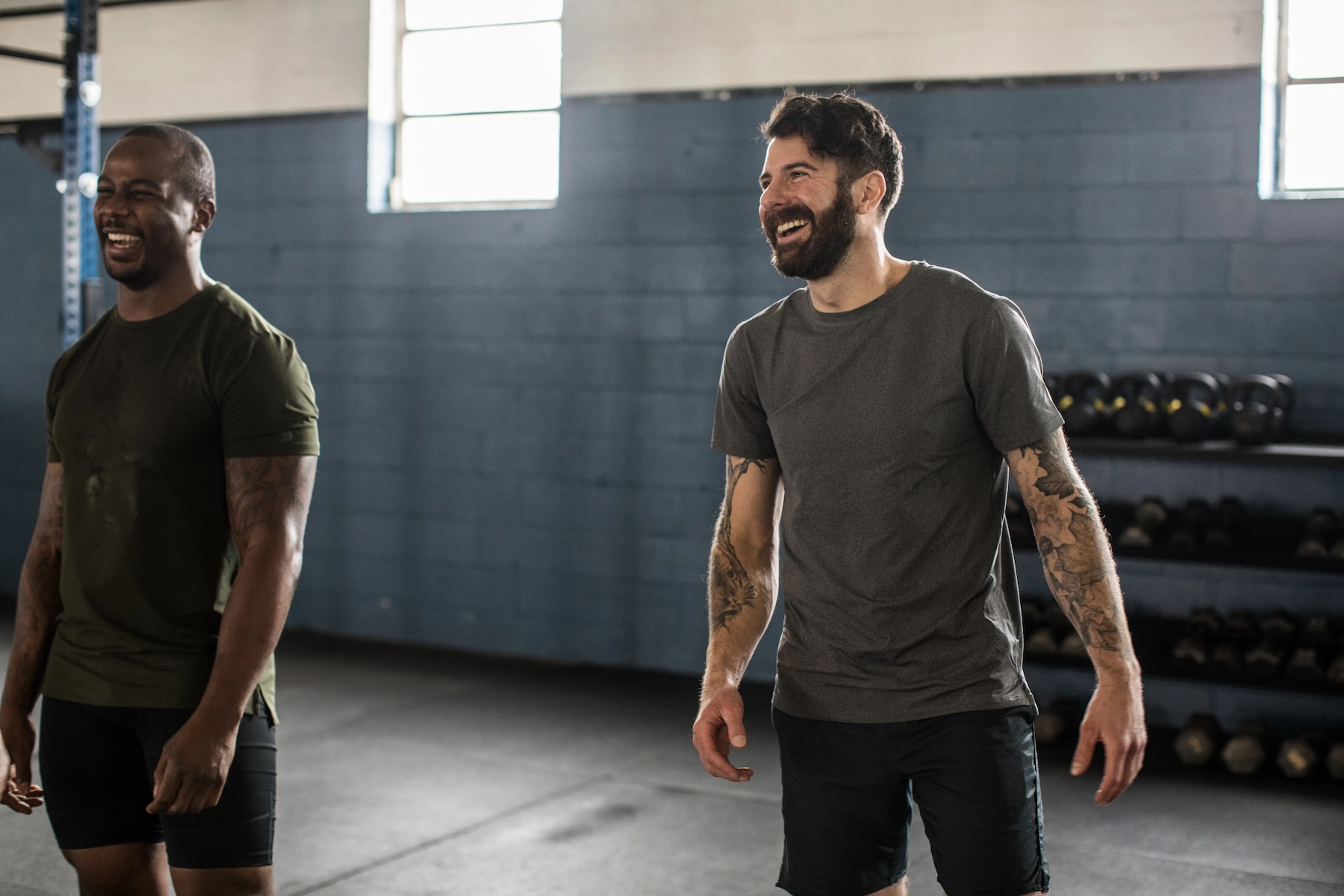 Two men laughing together at the gym. They feel good after lifting weights.