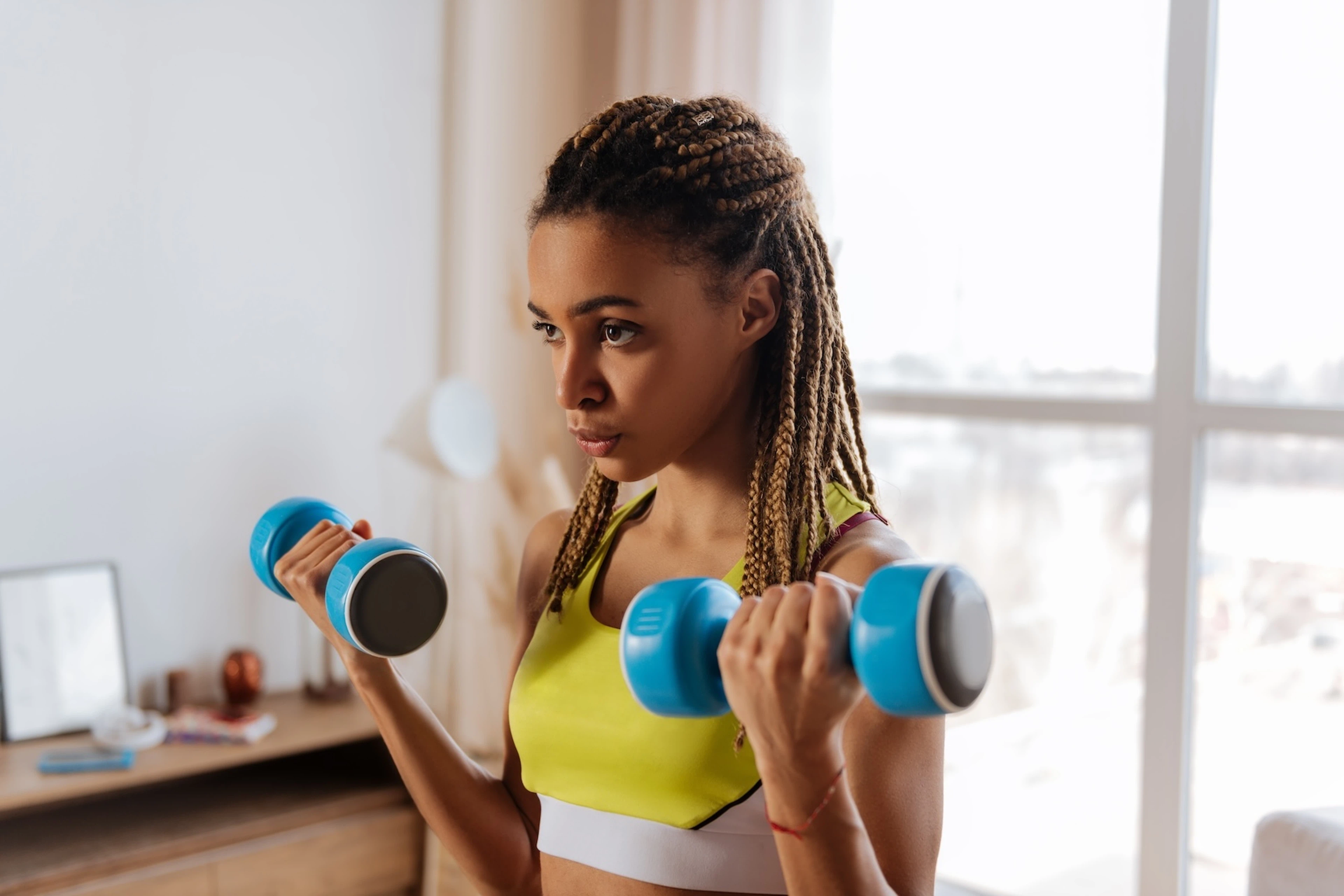 A young woman doing dumbbell bicep curls at home.