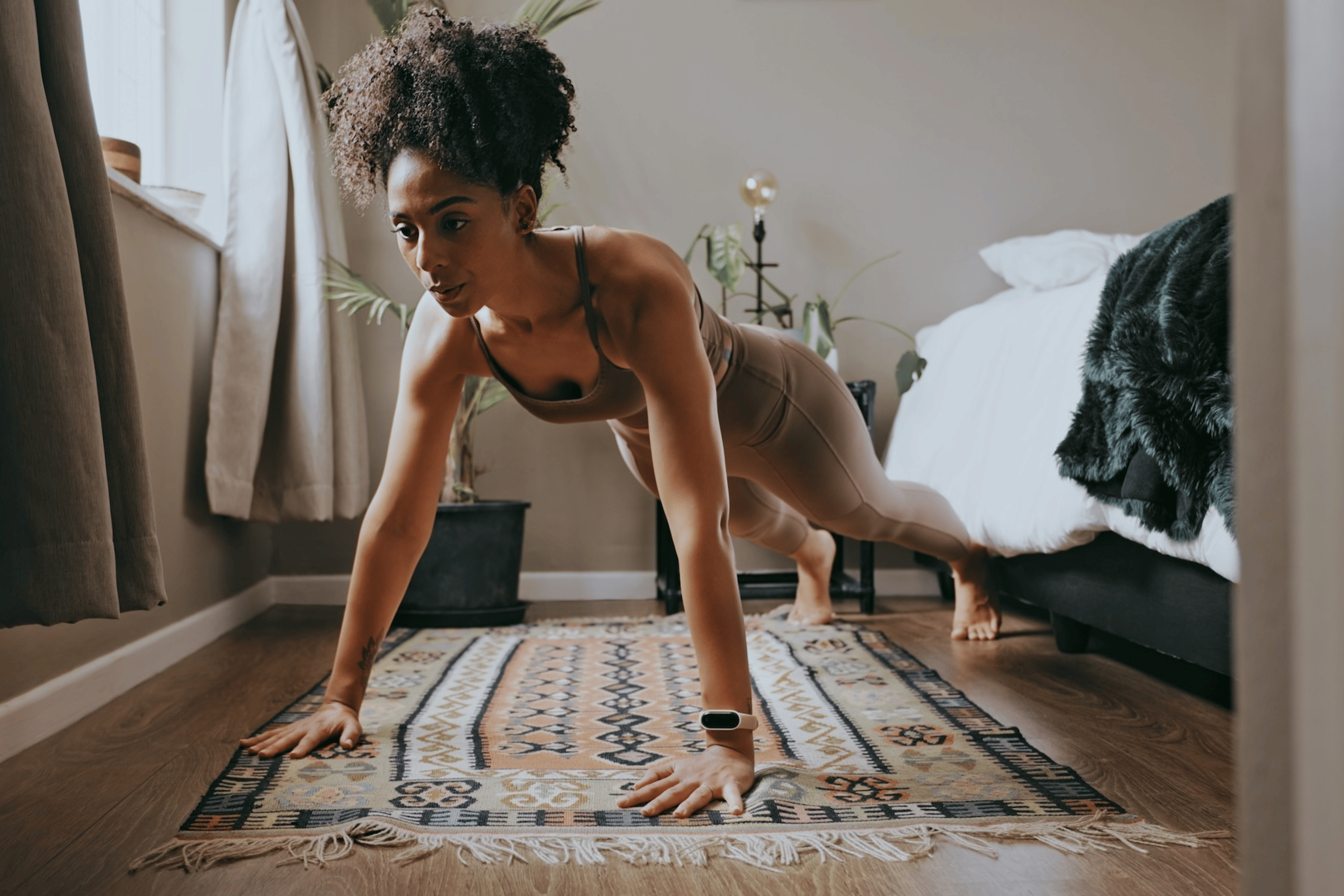 A woman in a high-plank position next to her bed. She's about to do push-ups before bed.