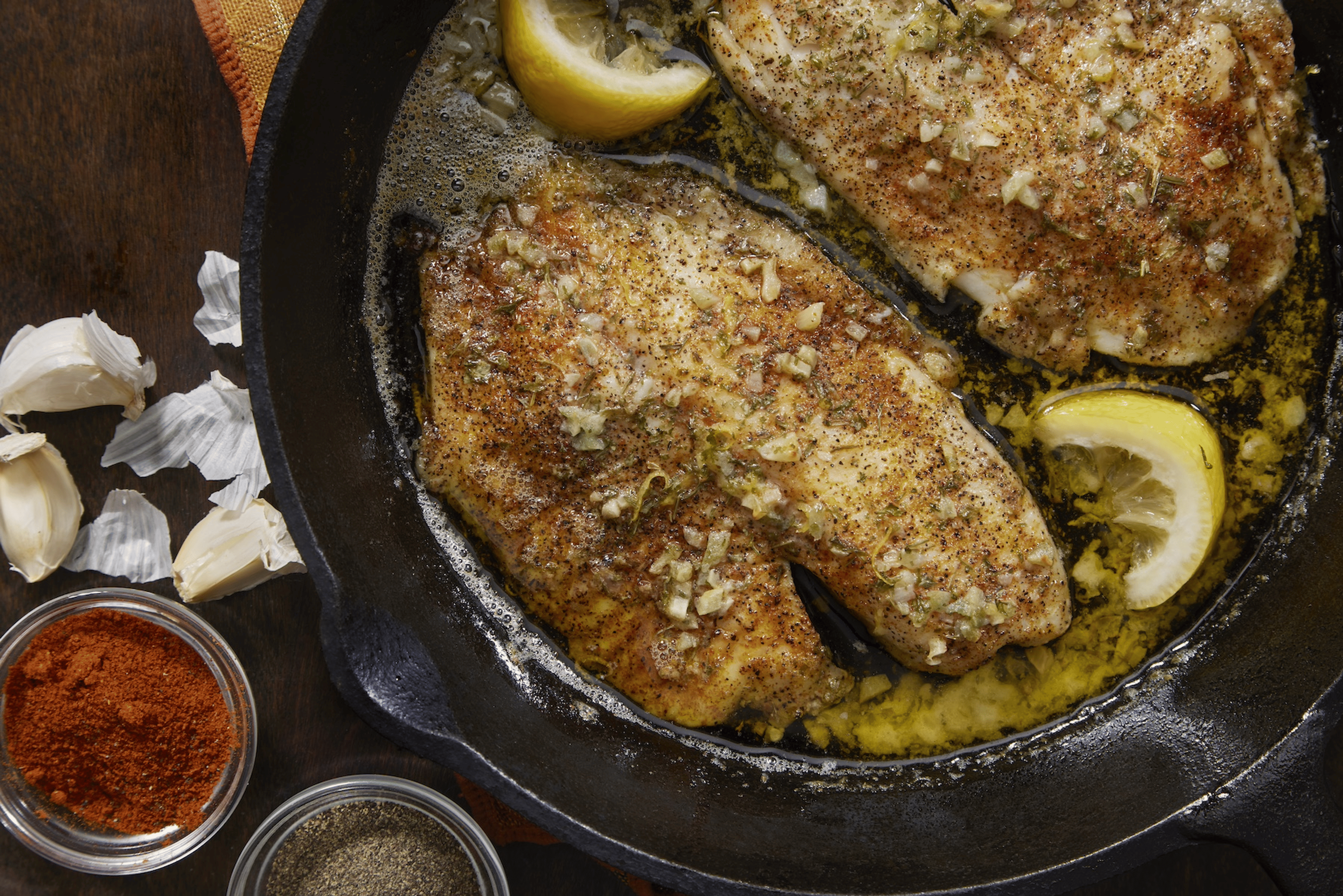 Baked tilapia (a lean protein) in a garlic butter sauce in a pan.