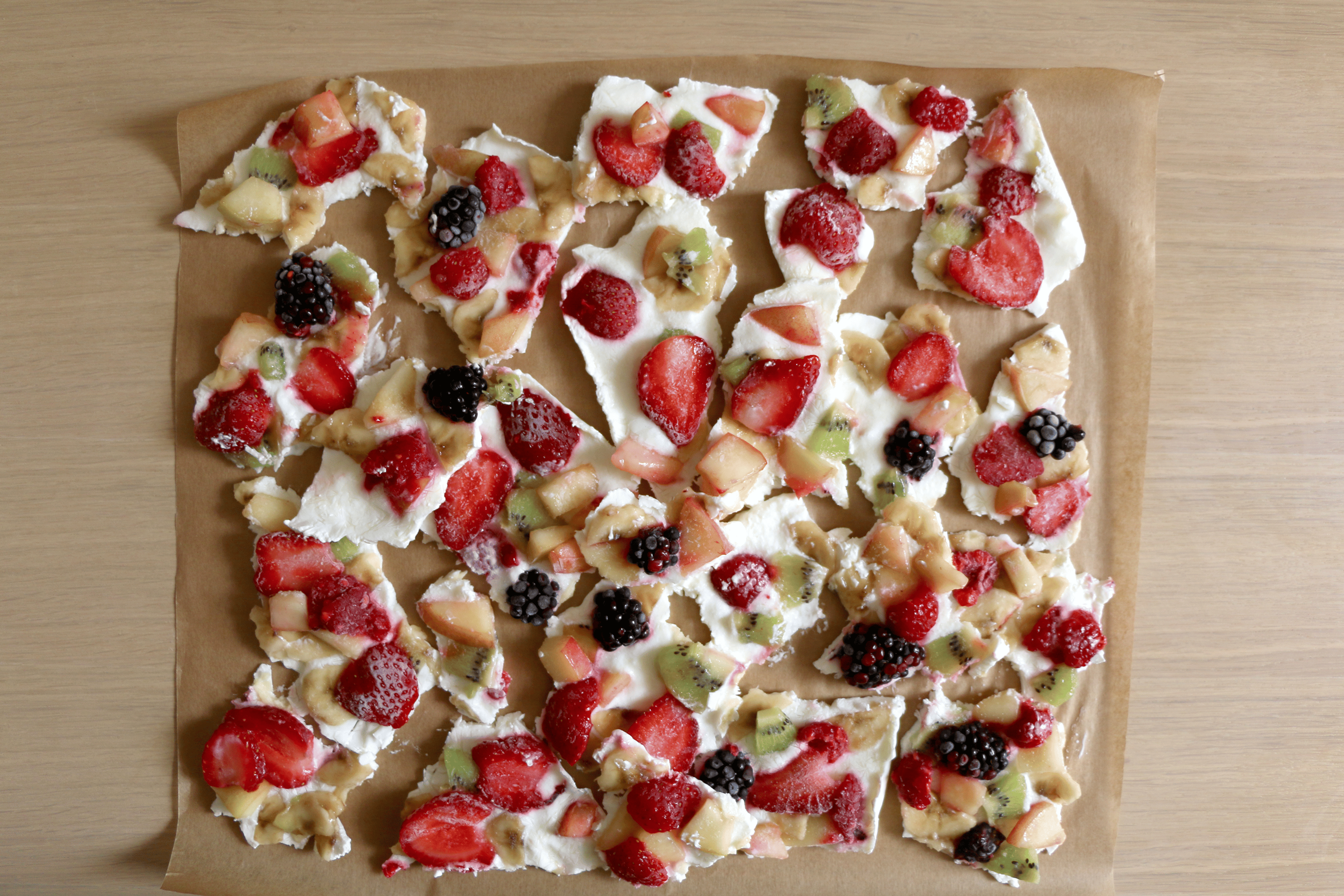 A tray of vegan Greek yogurt bark with various fruits in it like strawberry, banana, kiwi, blackberries, and raspberries. It's a high-protein vegan snack.