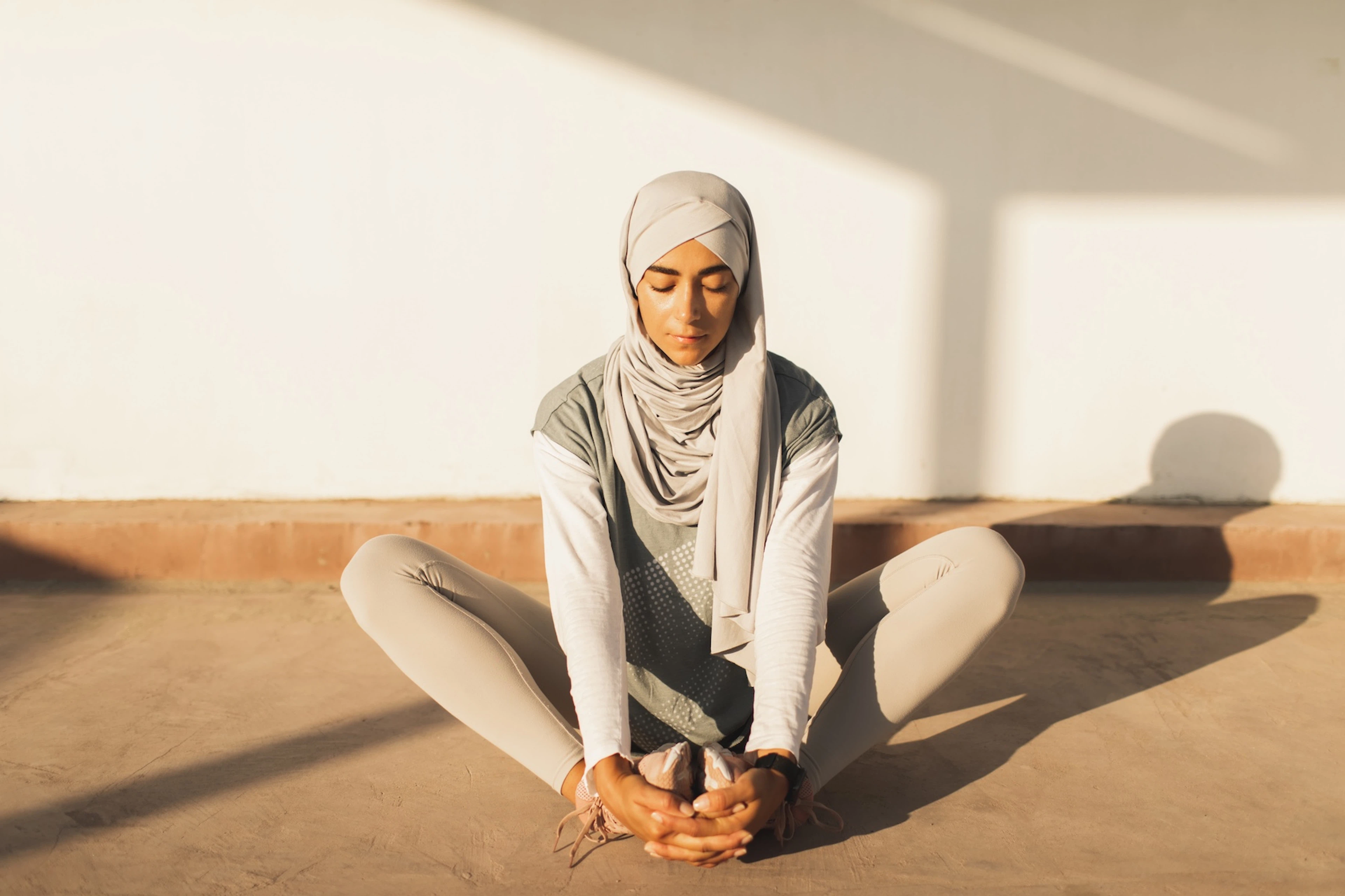 A person practicing meditation while sitting down in a lotus pose variation.