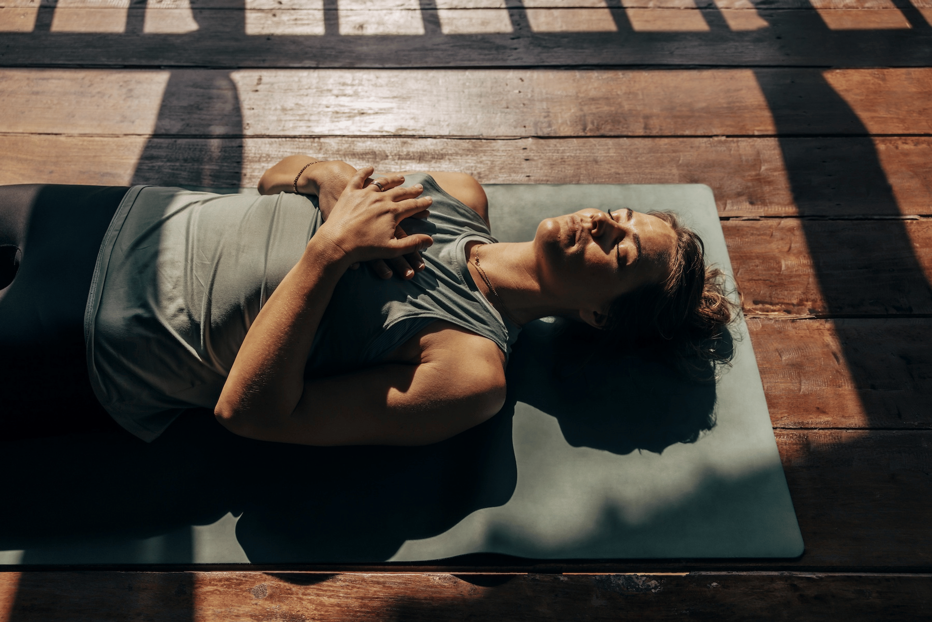 A woman lying down on a yoga mat and practicing self-compassion meditation.