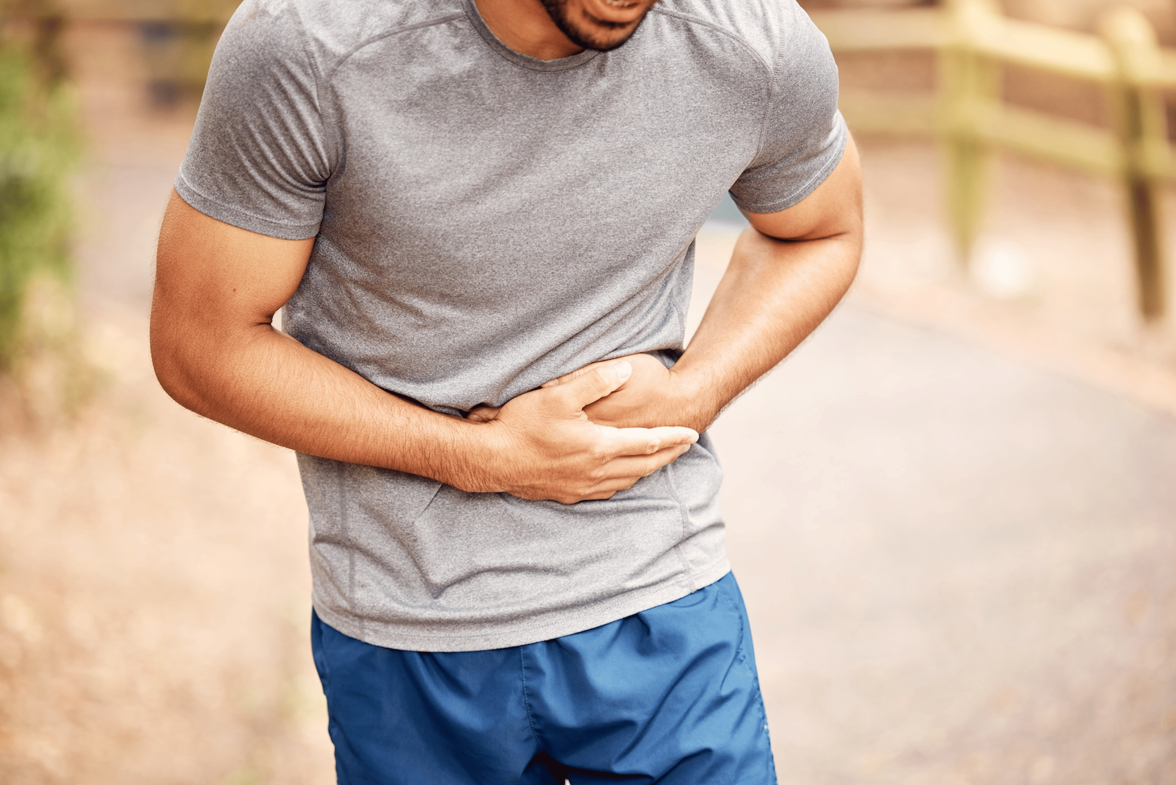 A man experiencing runner's stomach. He's holding his stomach with both hands.