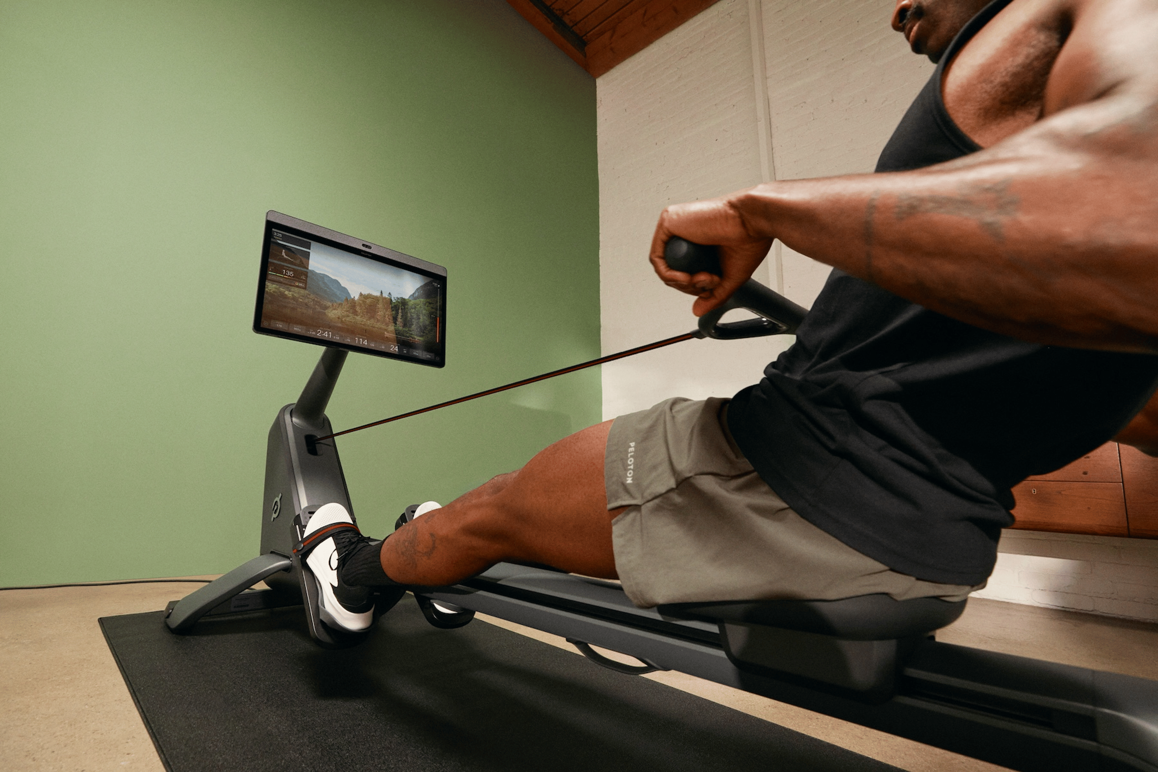 man learning how to use a rowing machine on a Peloton Row scenic class