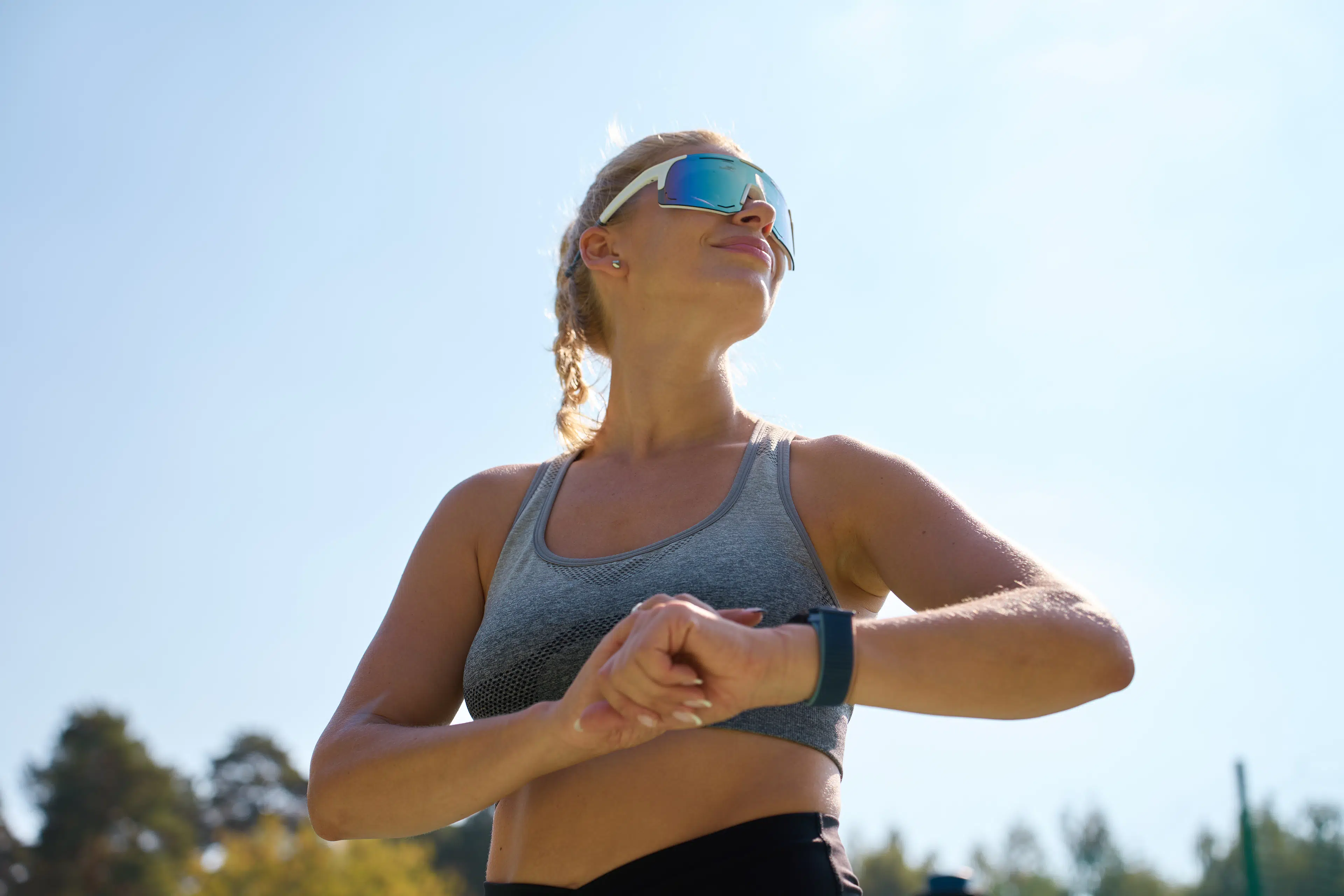 Runner in sunglasses checking her watch during a shakeout run on the day before a marathon.