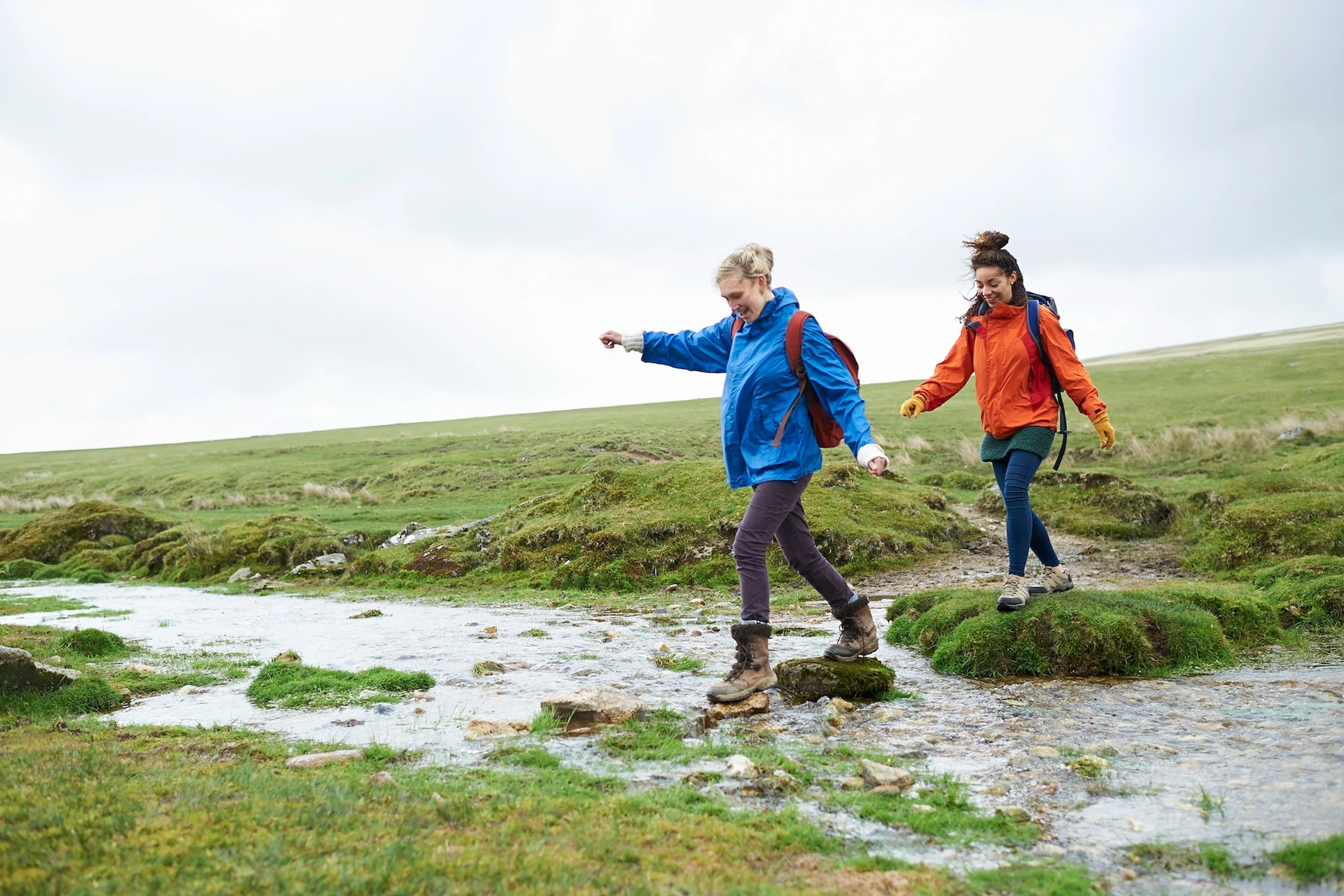 Two friends hiking in a green field.
