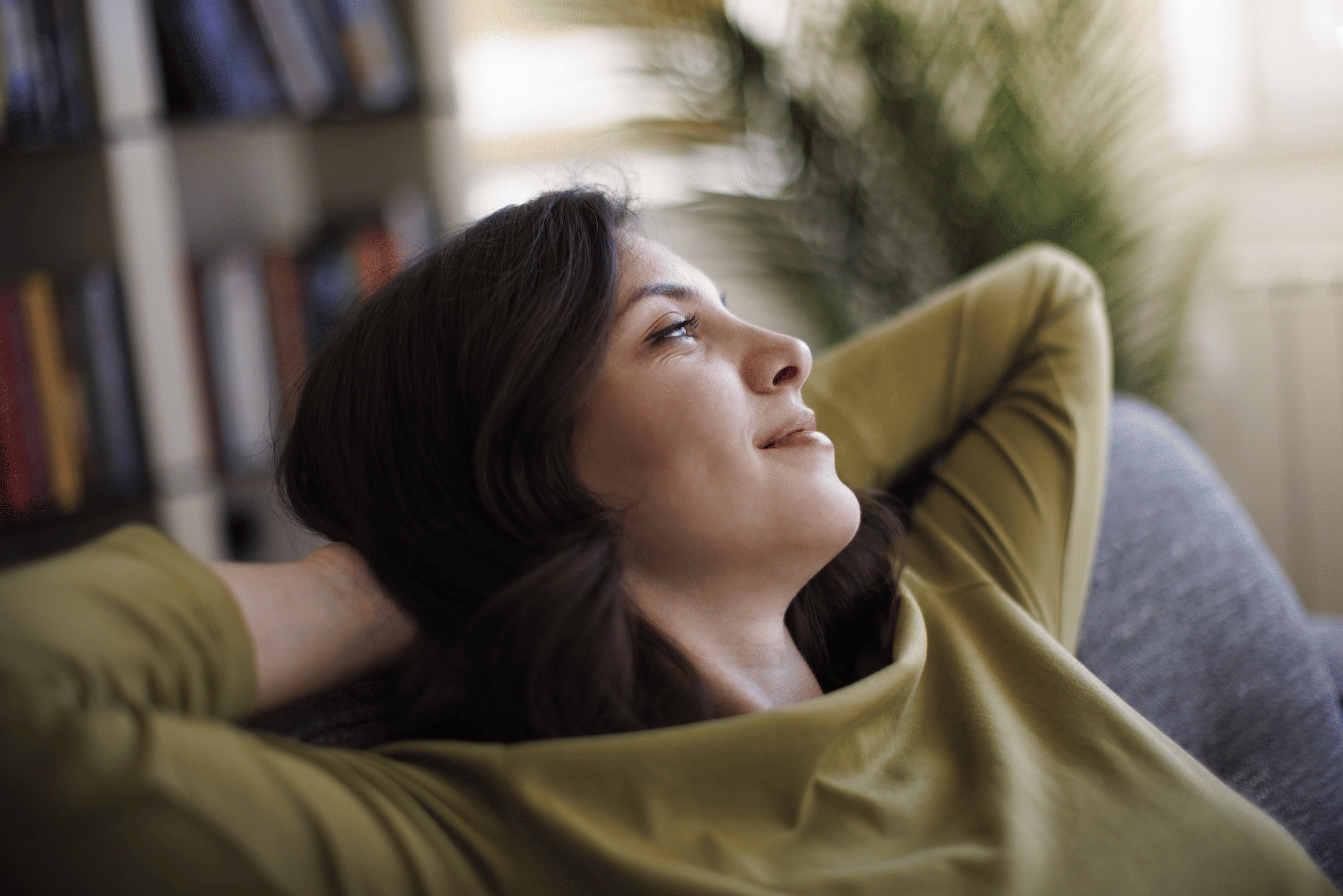 A woman relaxing at home, meditating with her eyes open in a soft gaze.