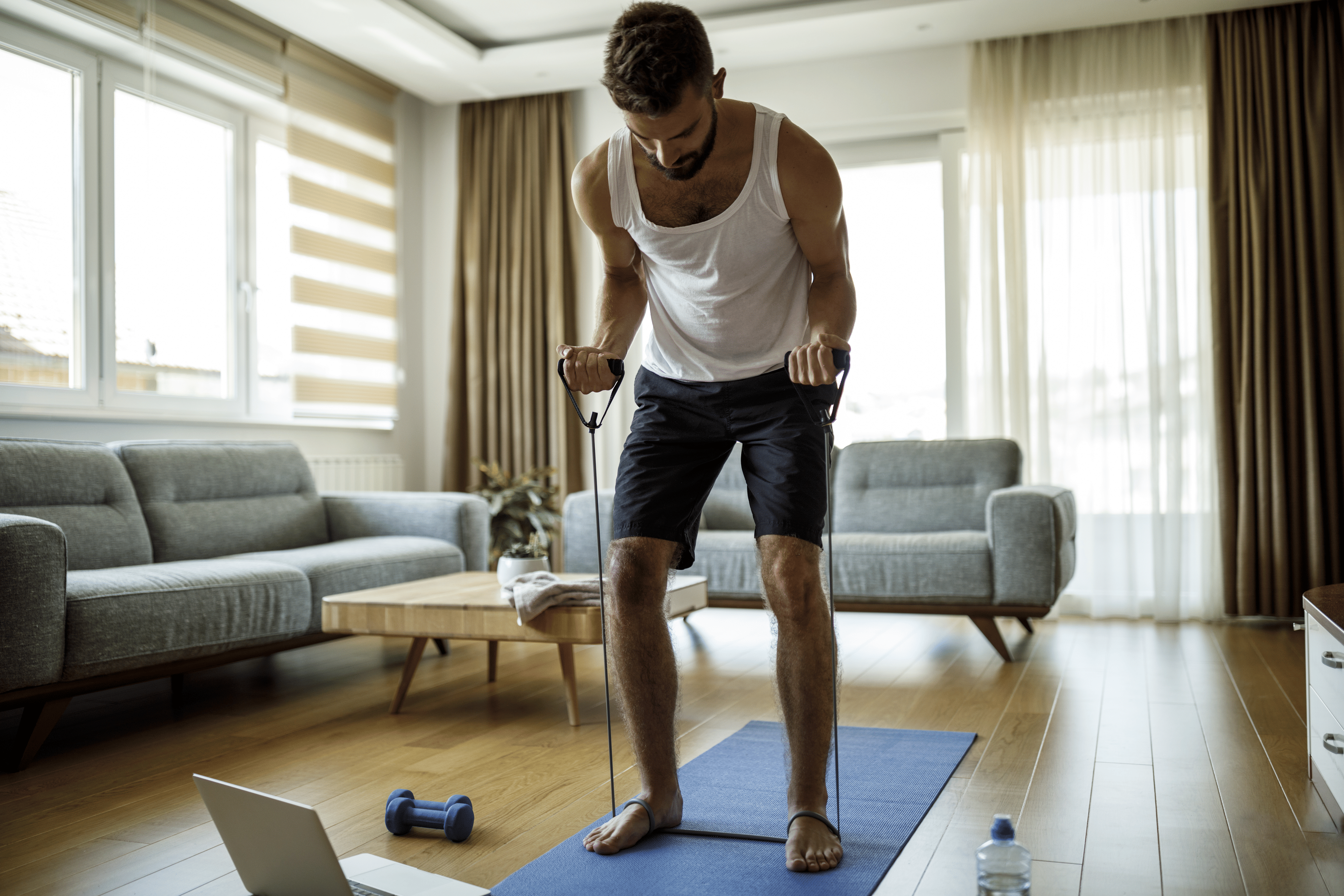 Man working out at home with resistance bands and weights 