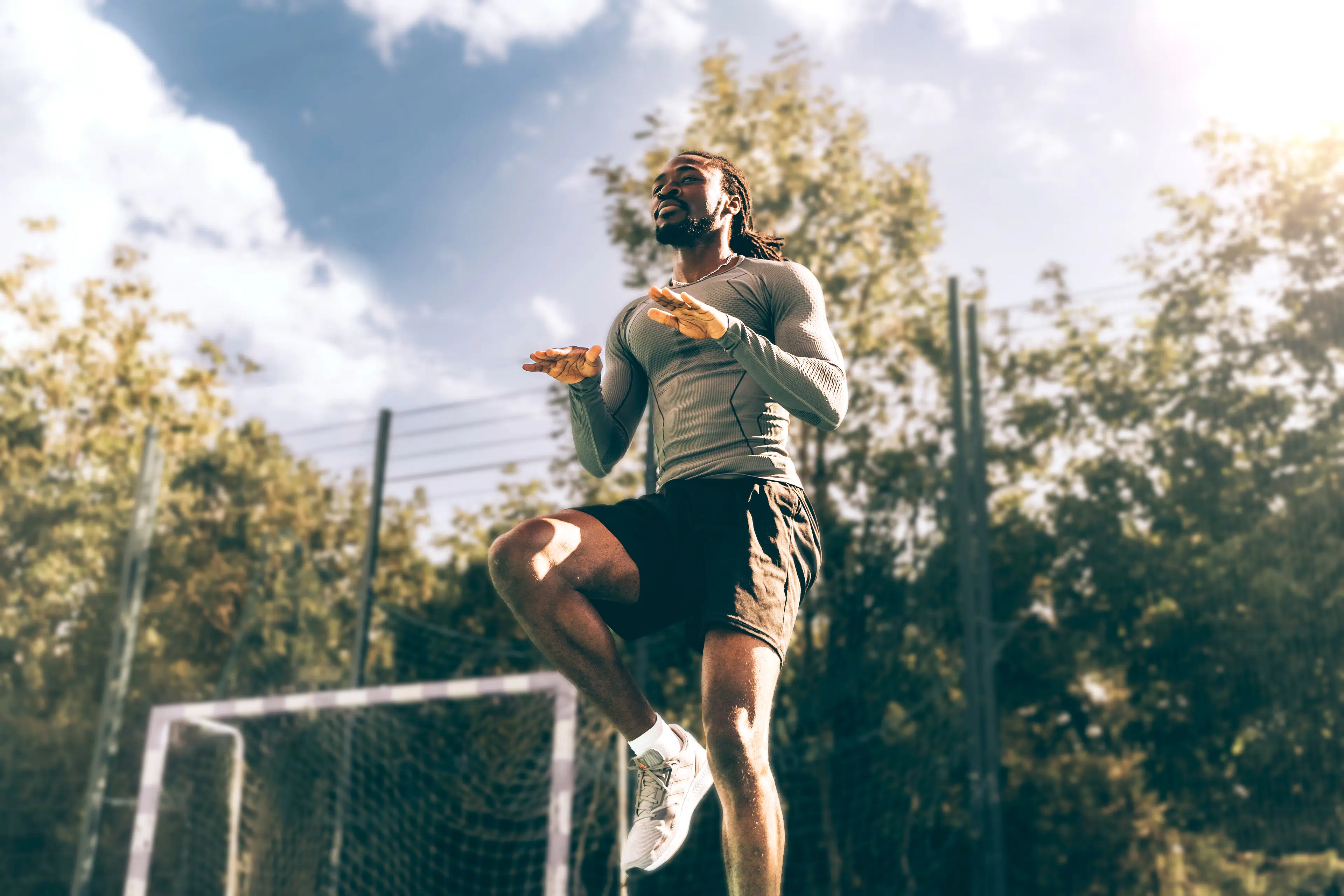 Man doing high knees warm-up exercise during an outdoor workout.