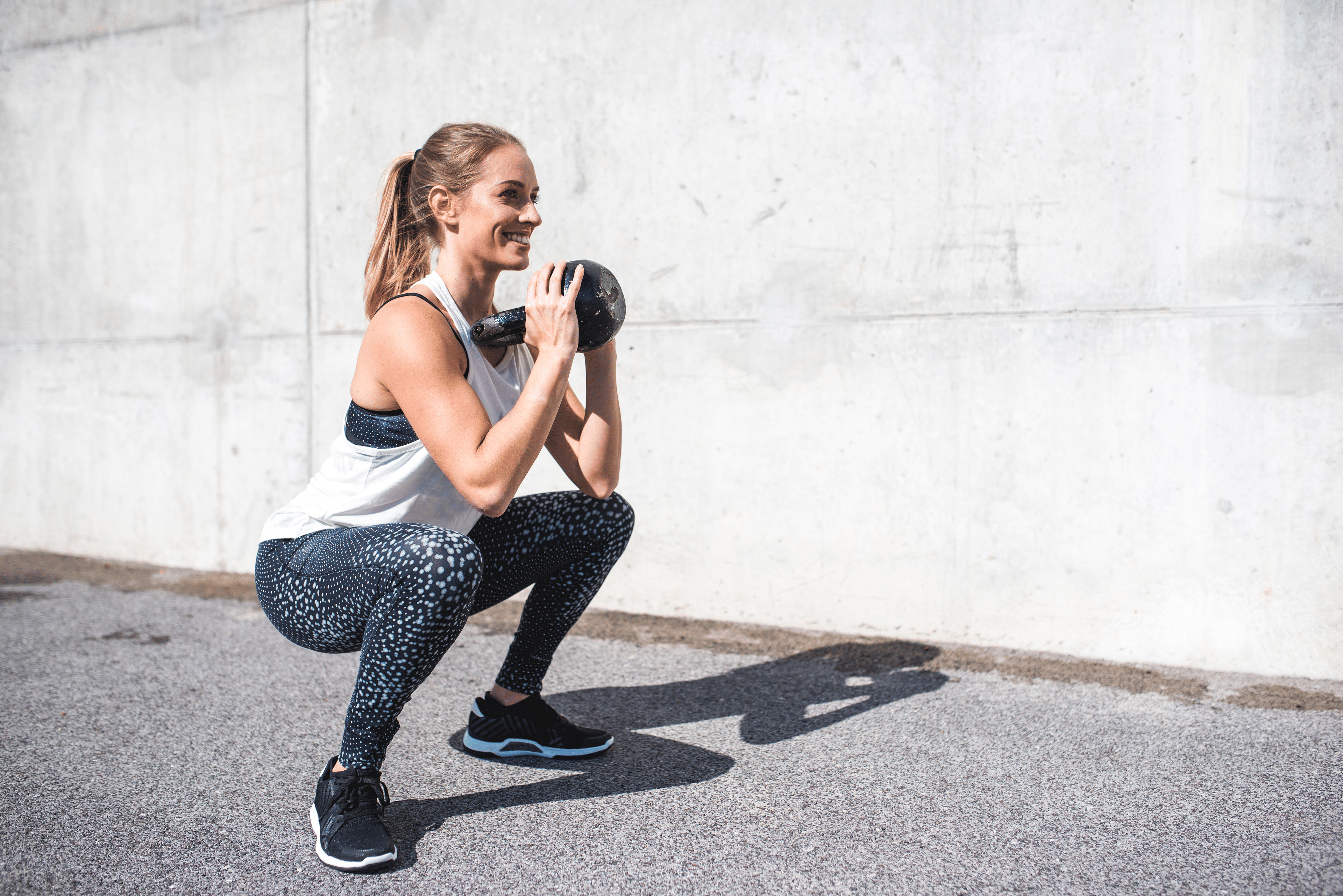 Woman does sumo squat while holding a kettlebell 