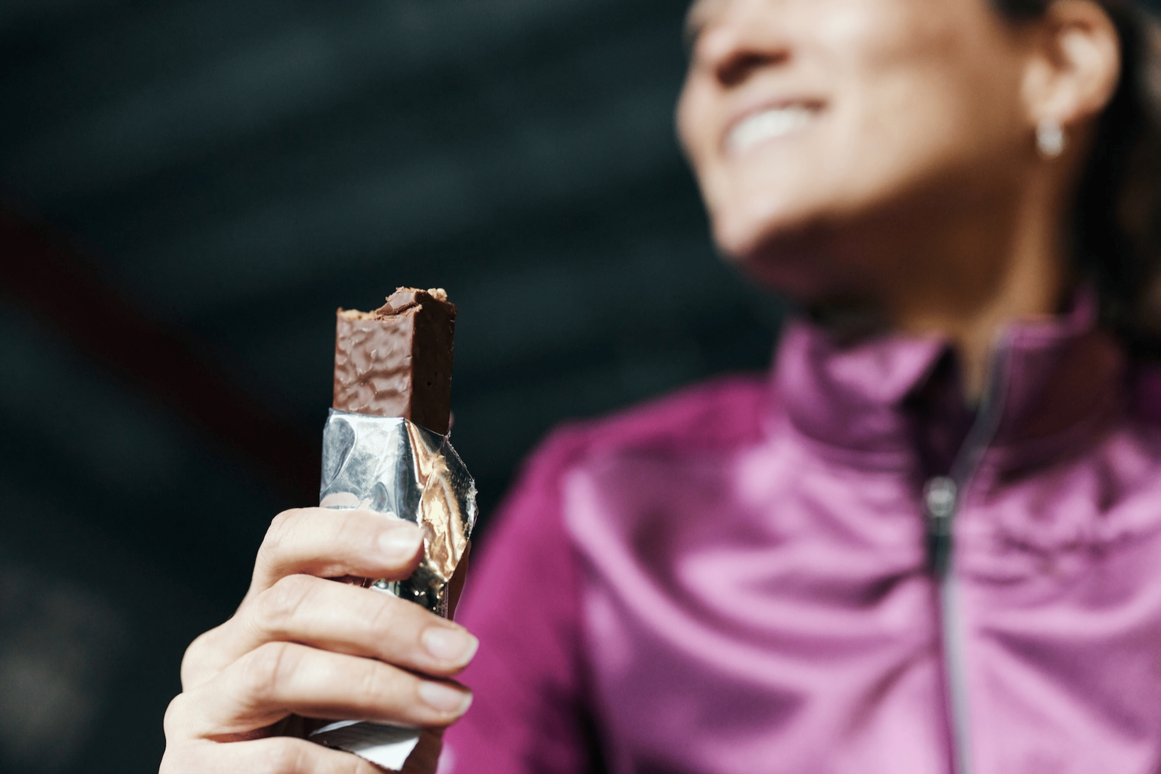 An close-up photo of an athlete holding a candy bar that she's taken a bite out of before her workout.