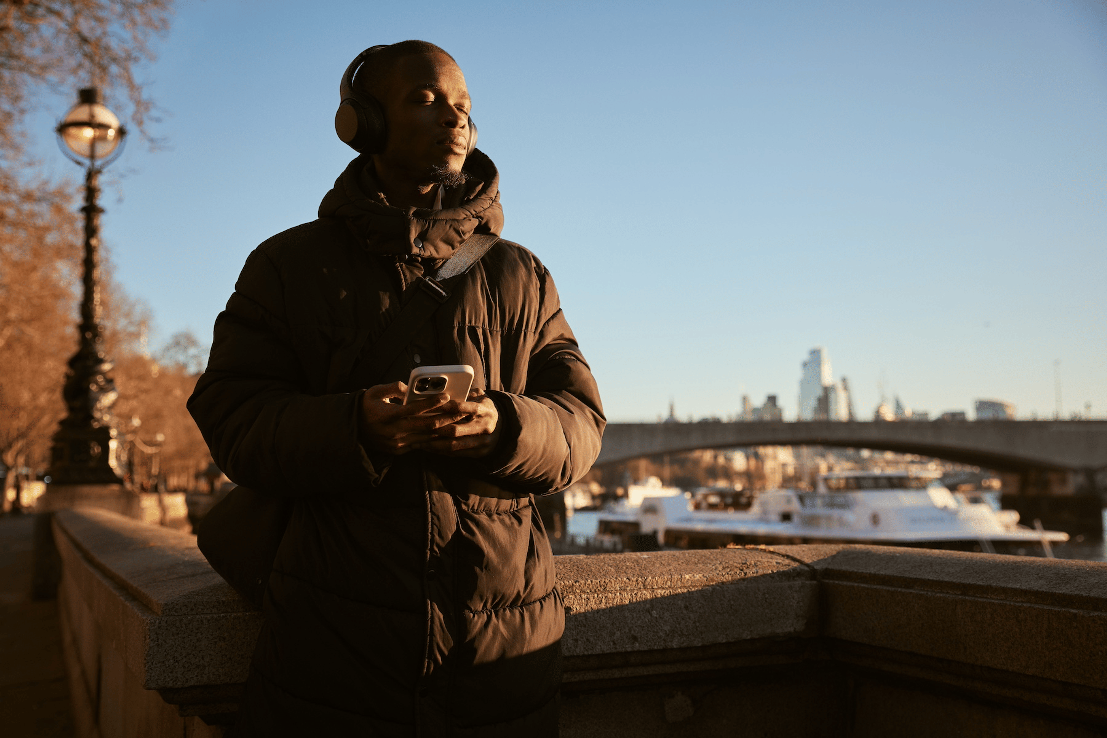A man peacefully meditating outside while standing up with his eyes closed.