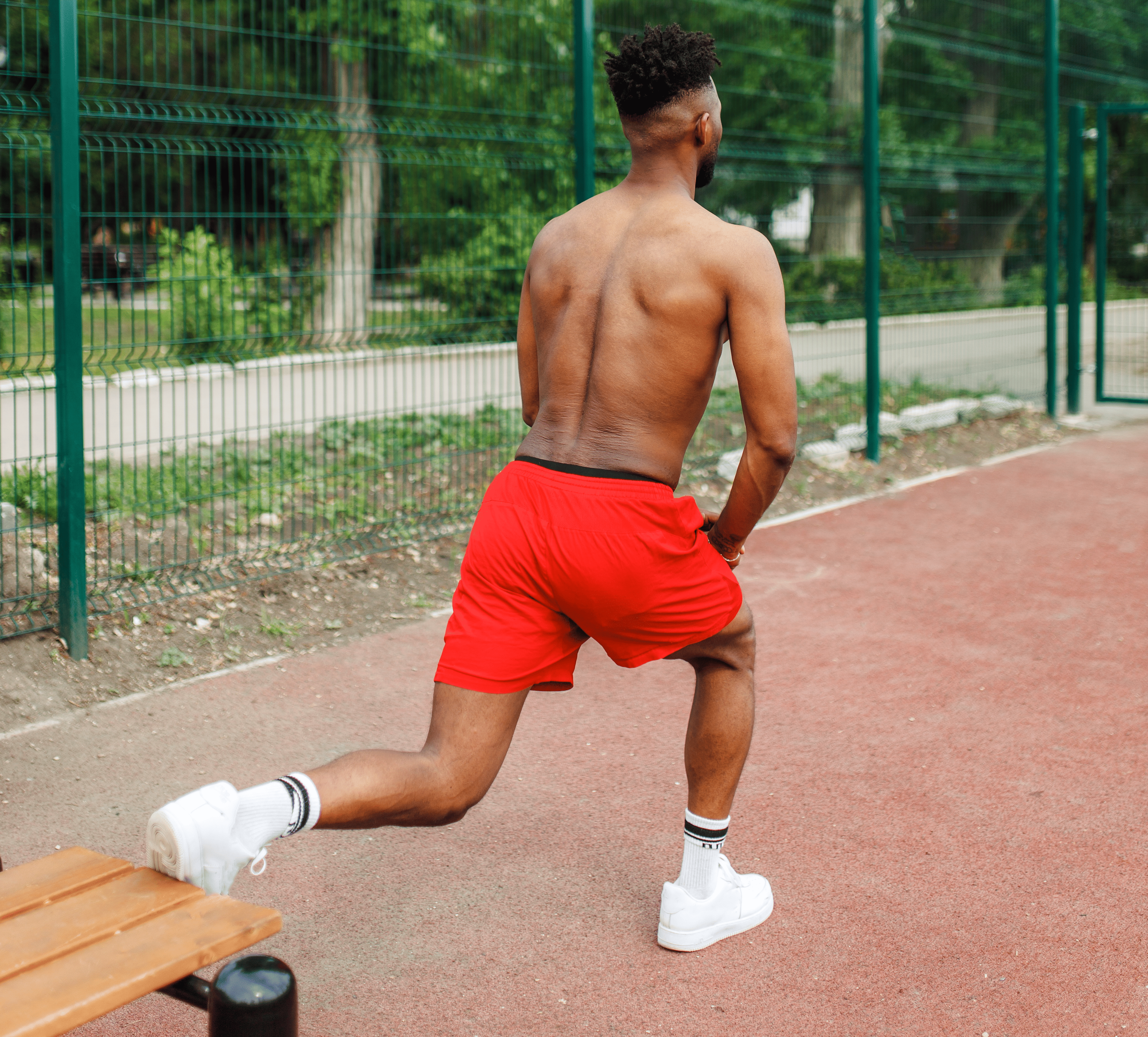 Man doing Bulgarian split squats on a park bench during a no-equipment full body workout.