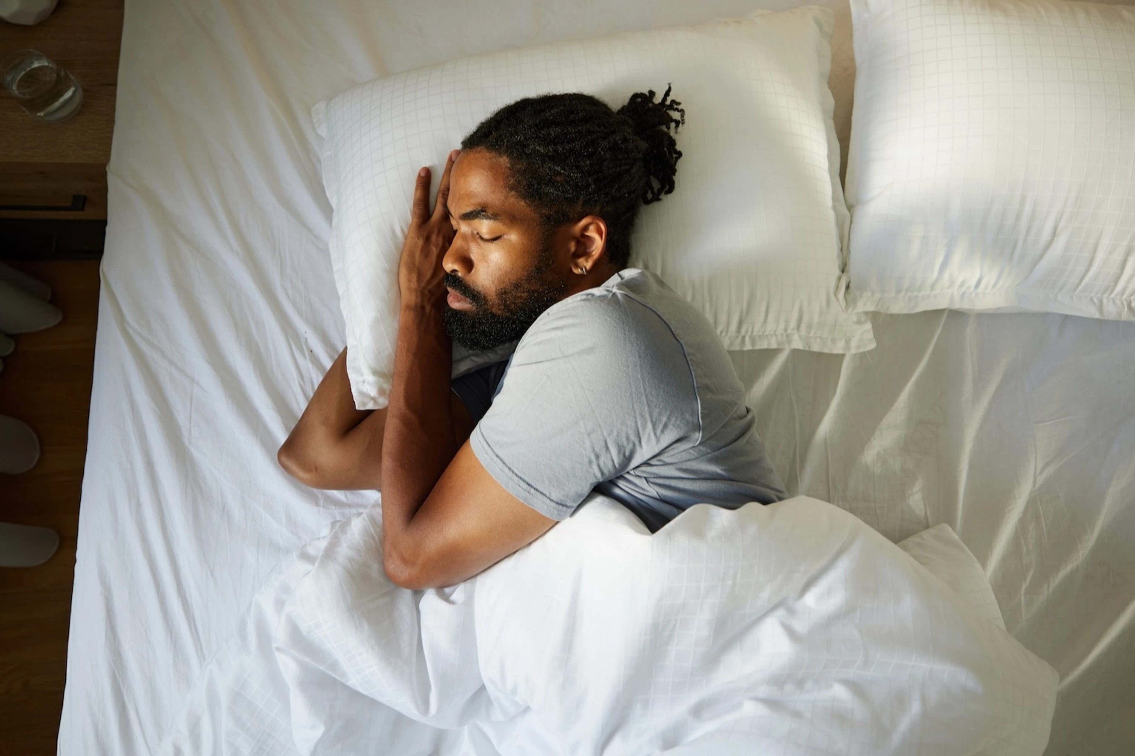 A man sleeping soundly in bed, lying on his side.