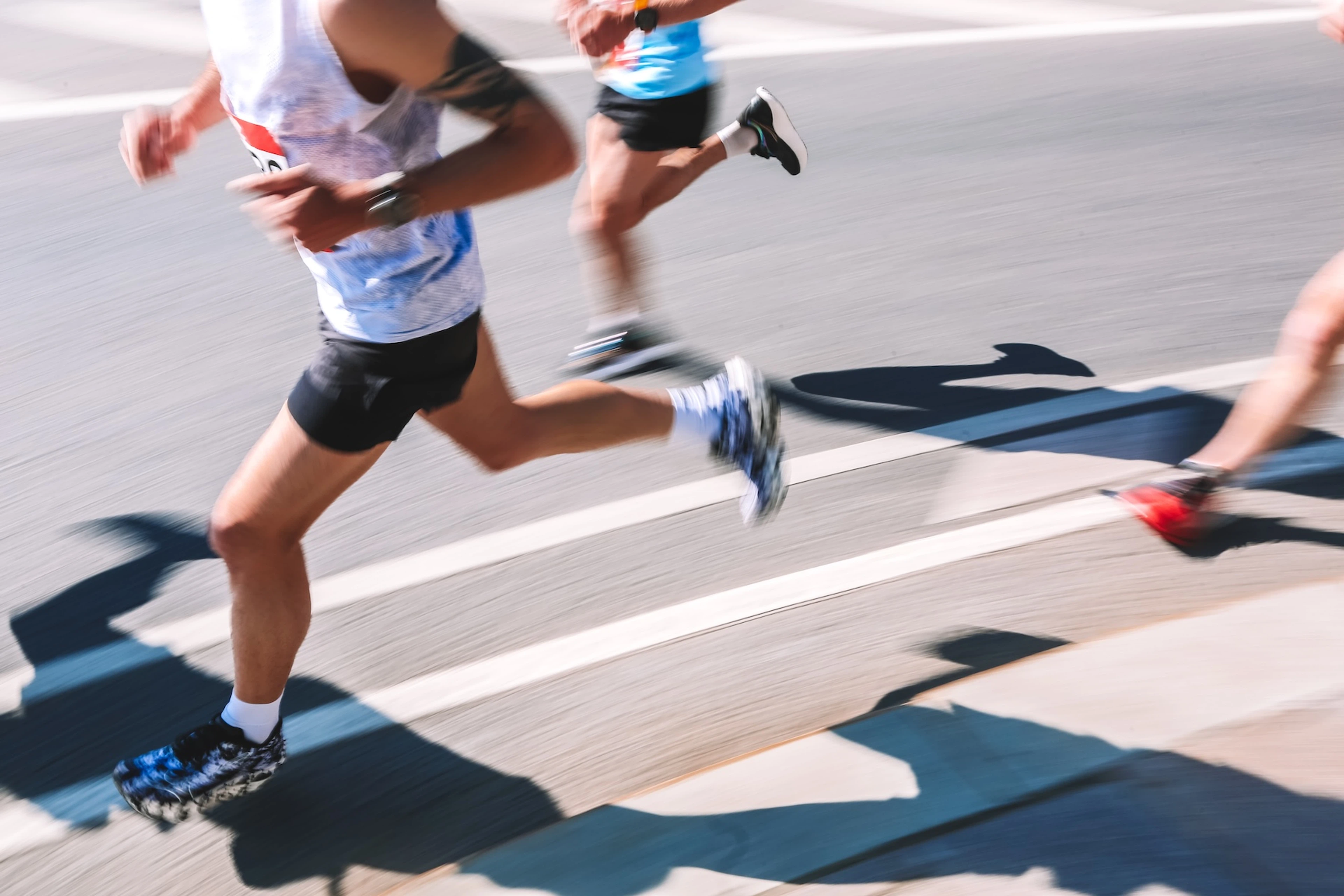 A close-up photo of runners' lower bodies quickly running a marathon.
