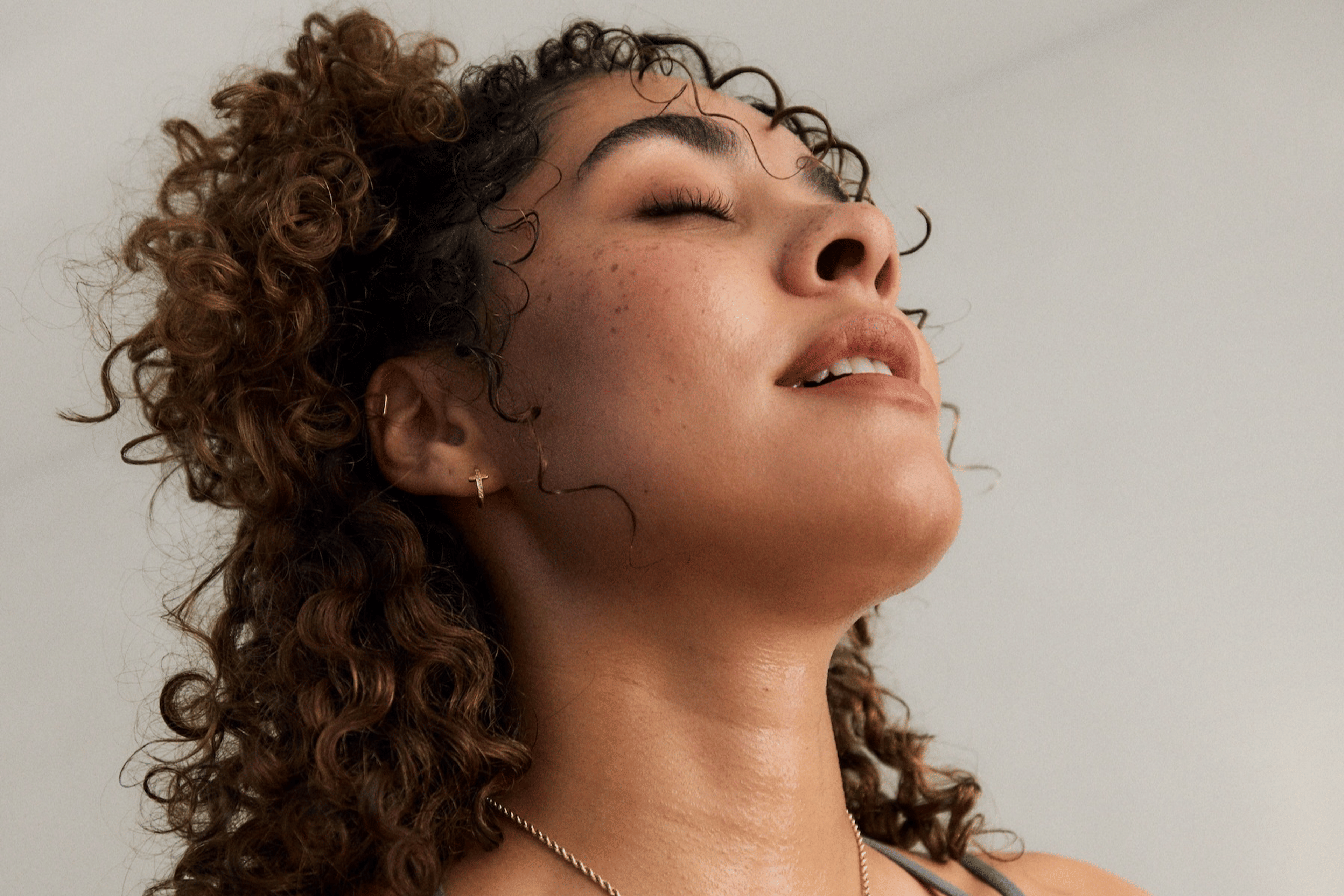 A woman practicing breathwork. She's breathing deeply through her mouth and closing her eyes.