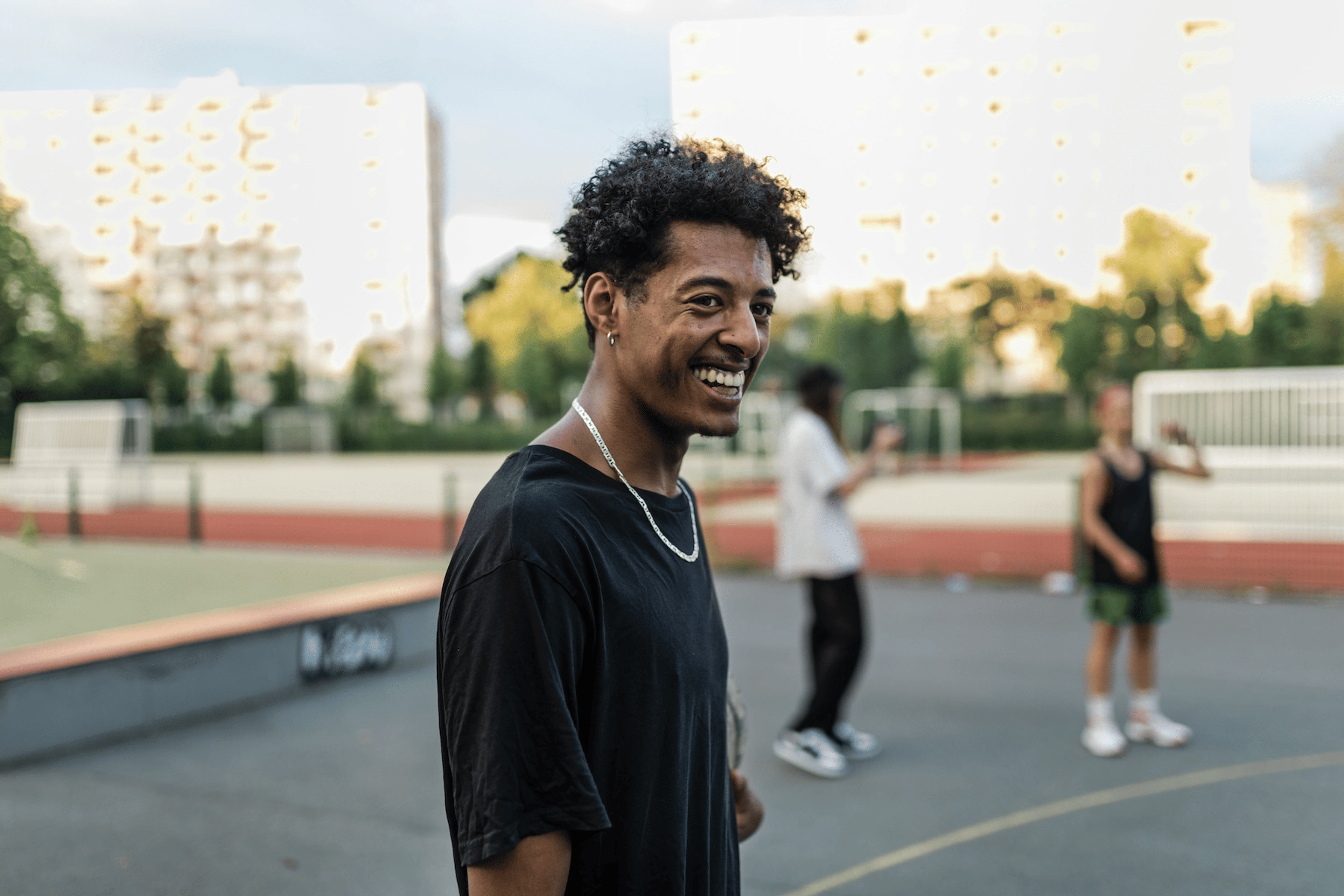 A man smiling while getting active with friends in an outdoor park. 
