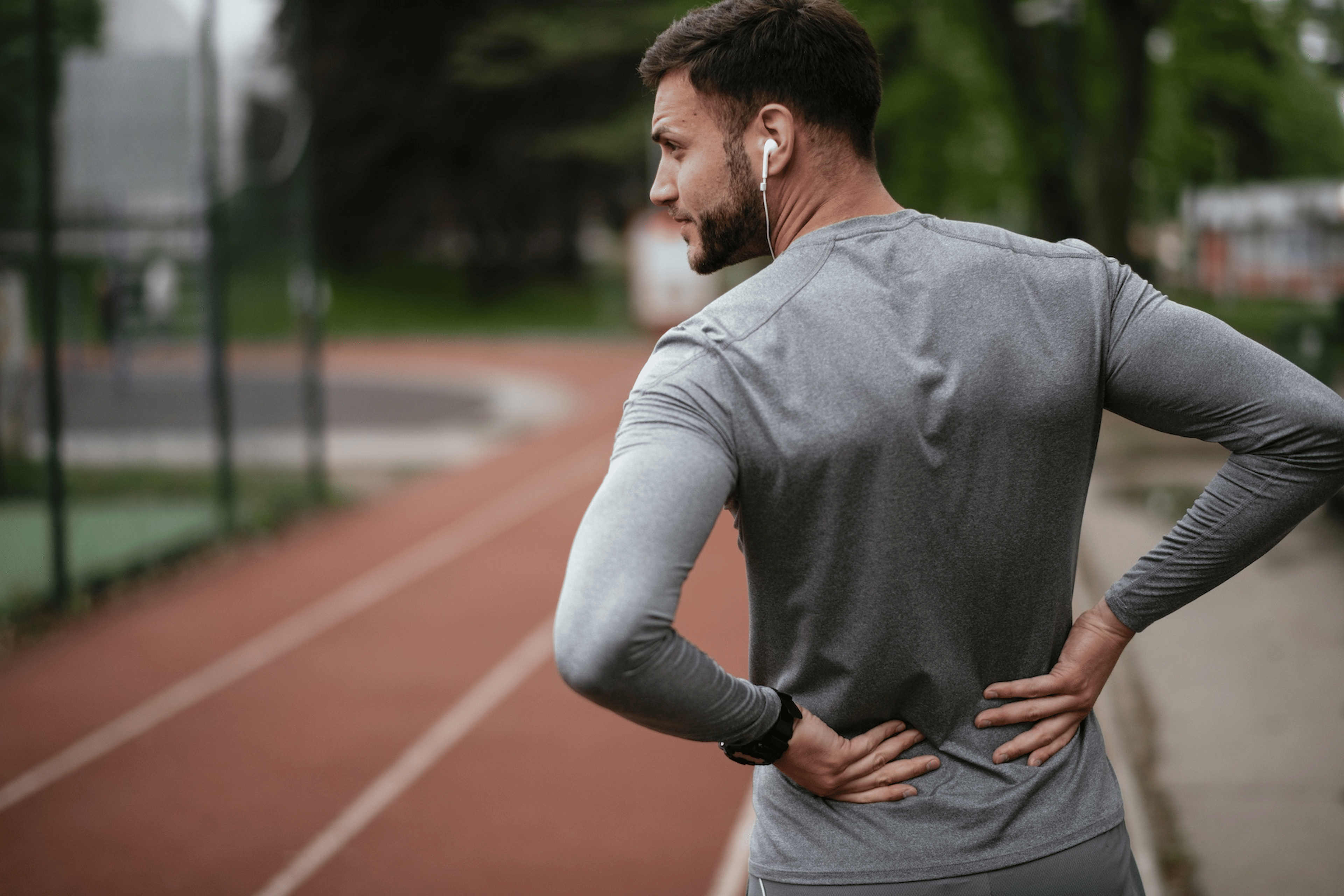 A runner holding his lower back after going for a track run. His lower back is hurting after running.