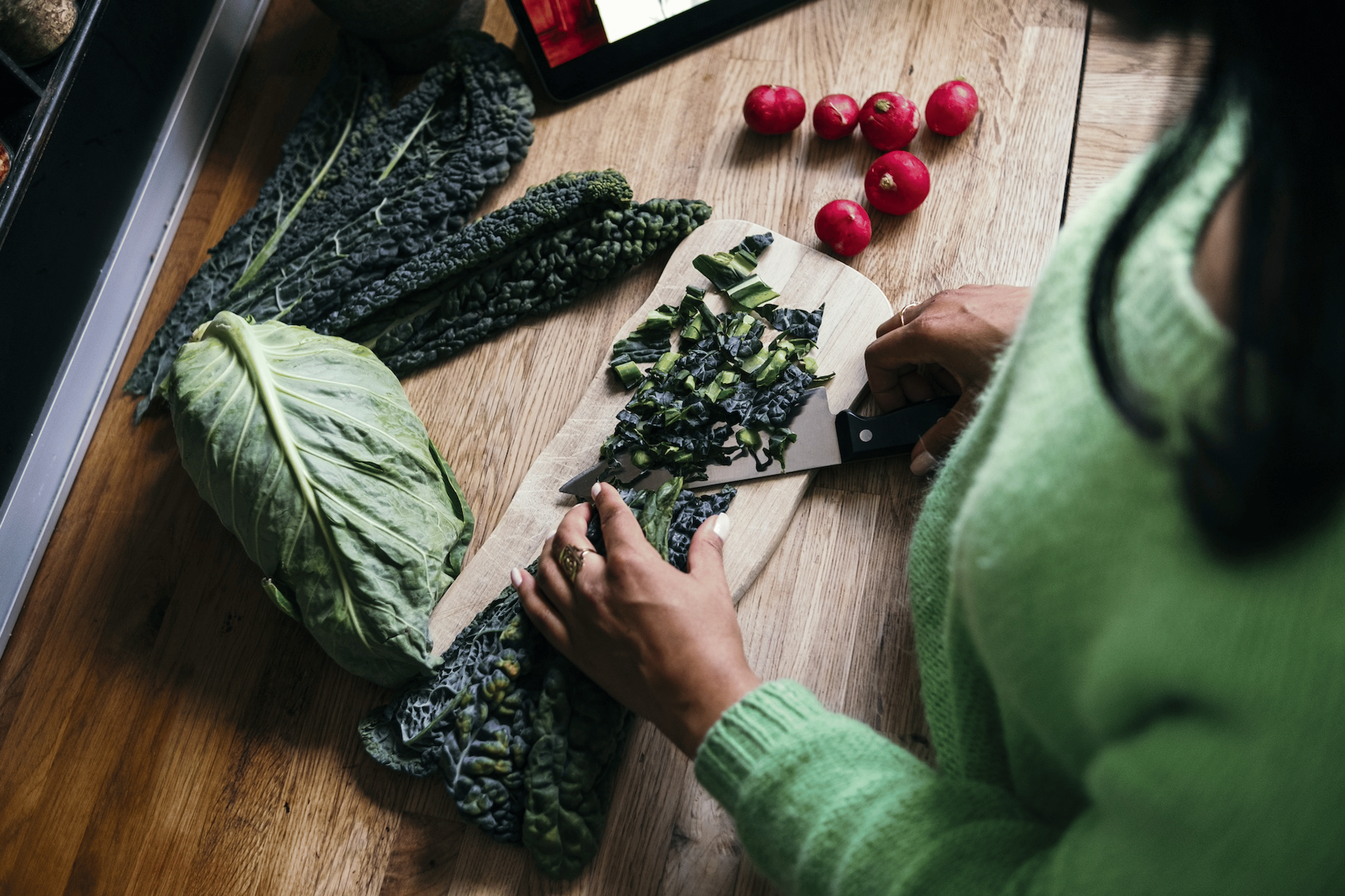 A woman chopping up kale on a cutting board. Kale is a high-protein vegetable.