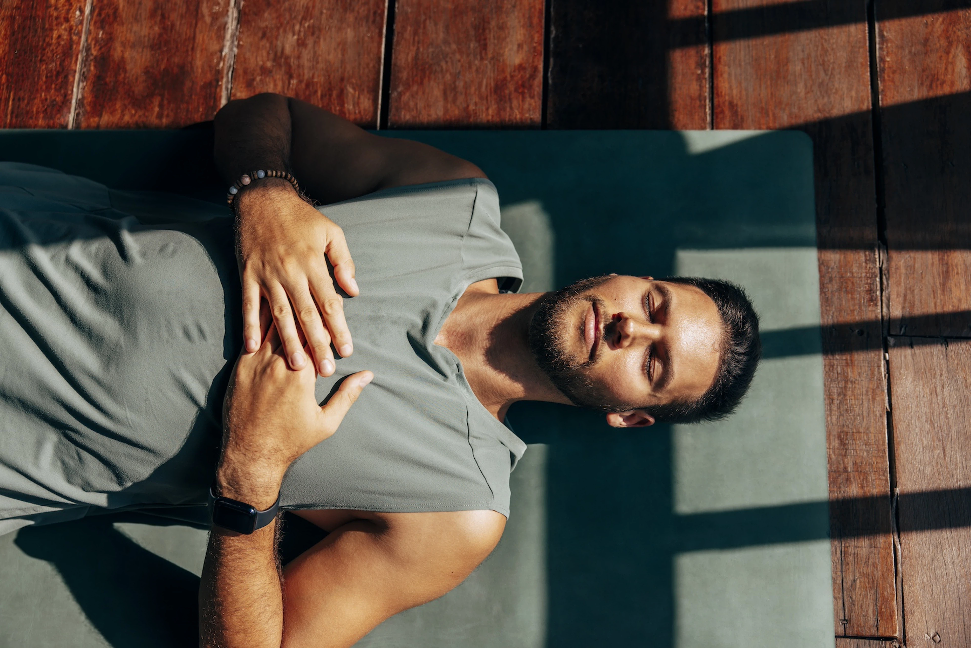A man lying down on a yoga mat, peacefully practicing yoga.
