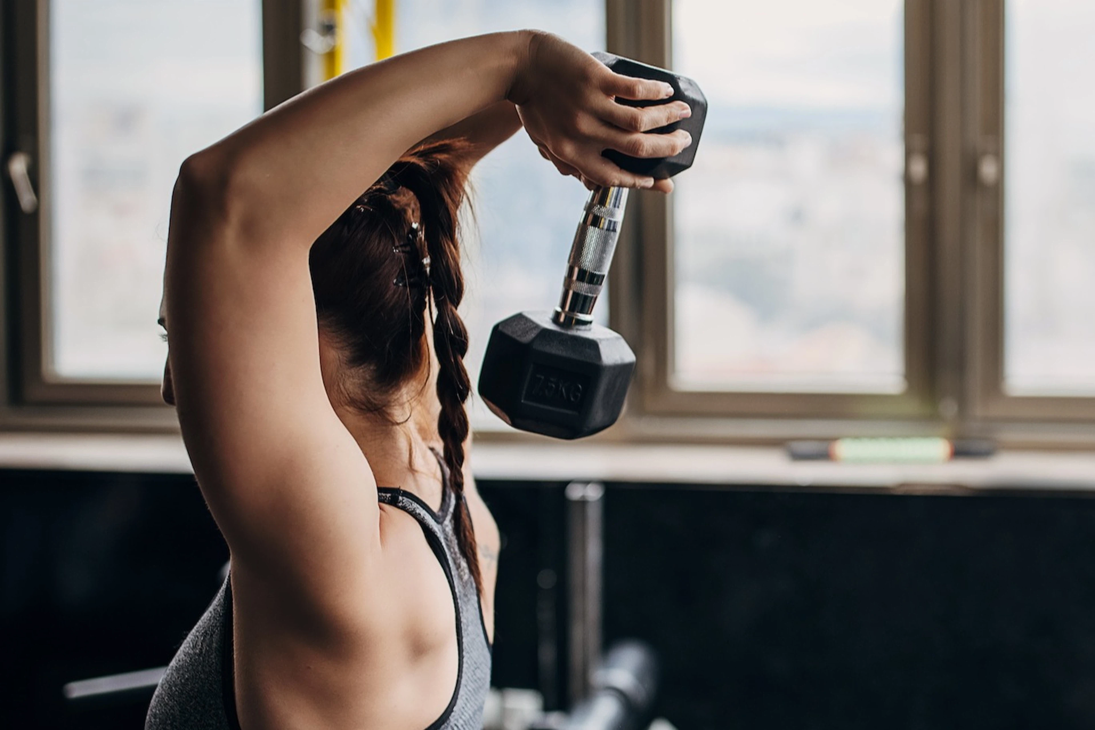 A woman training to failure while doing tricep extensions in a gym.