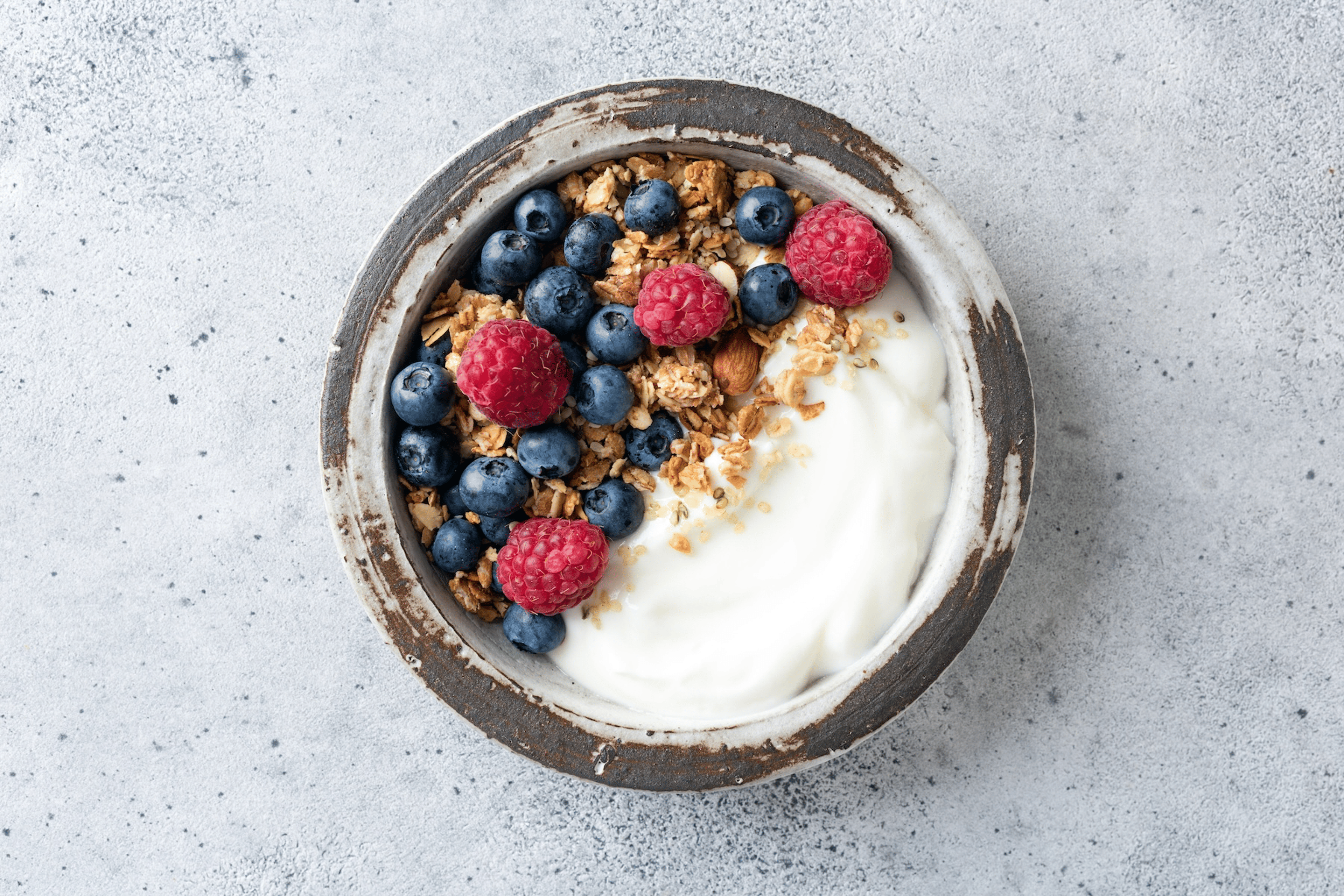 A bowl of Greek yogurt with granola and berries.