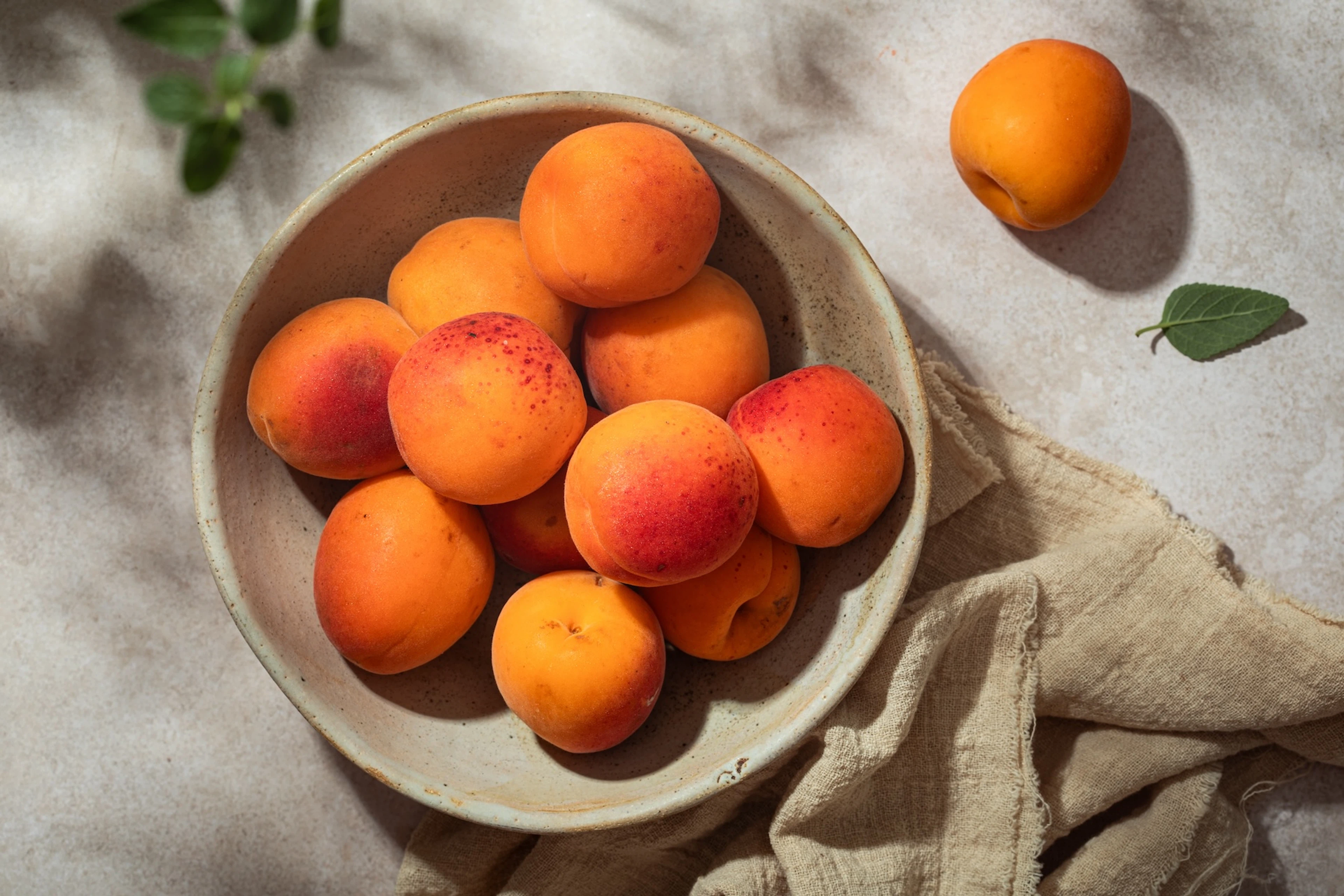 A bowl of apricots on a table.