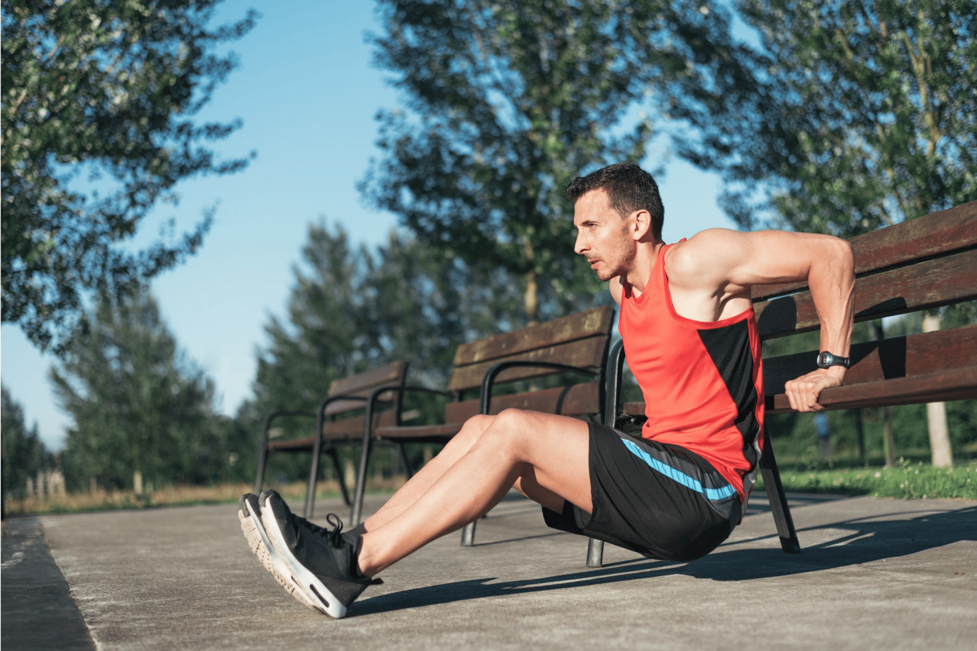 Man doing triceps dips on a park bench during a no-equipment full body workout.