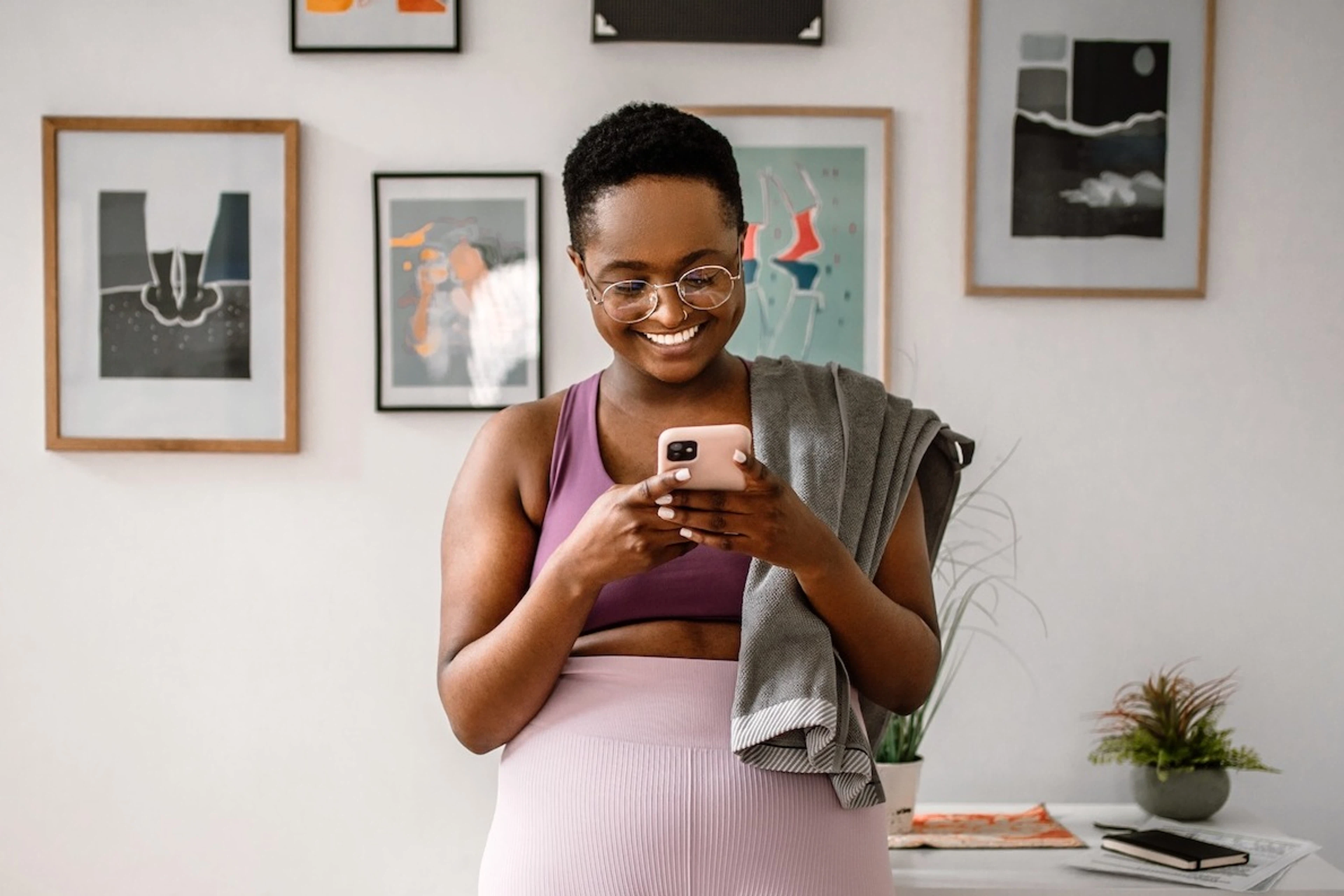 Woman smiling and looking at her phone, texting her virtual workout buddy after exercising.