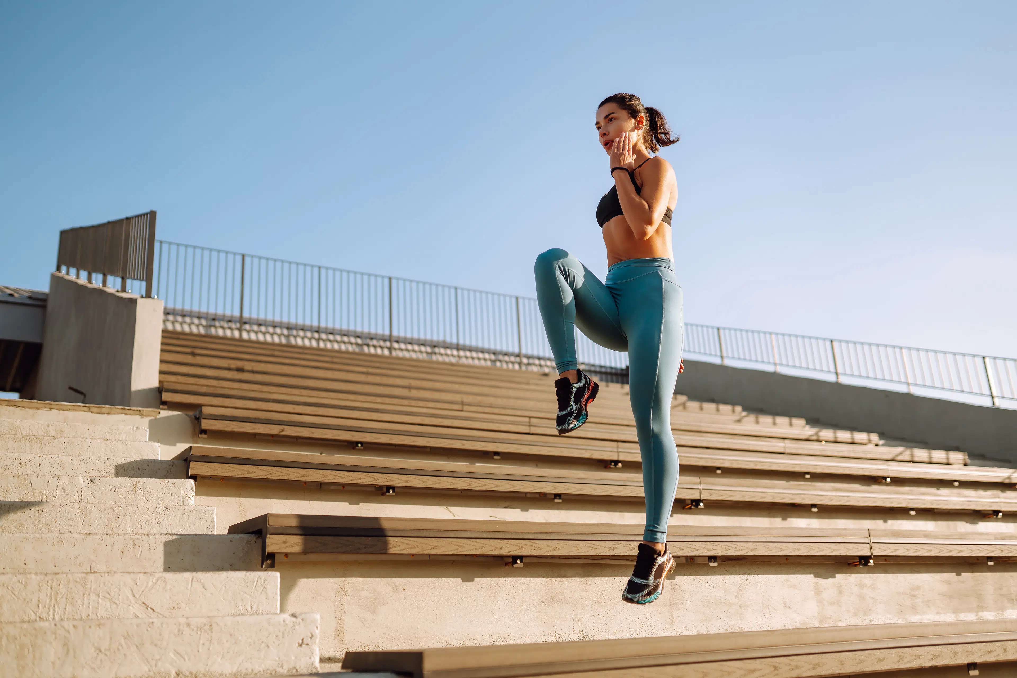 Woman doing knee up HIIT workout on bleachers 