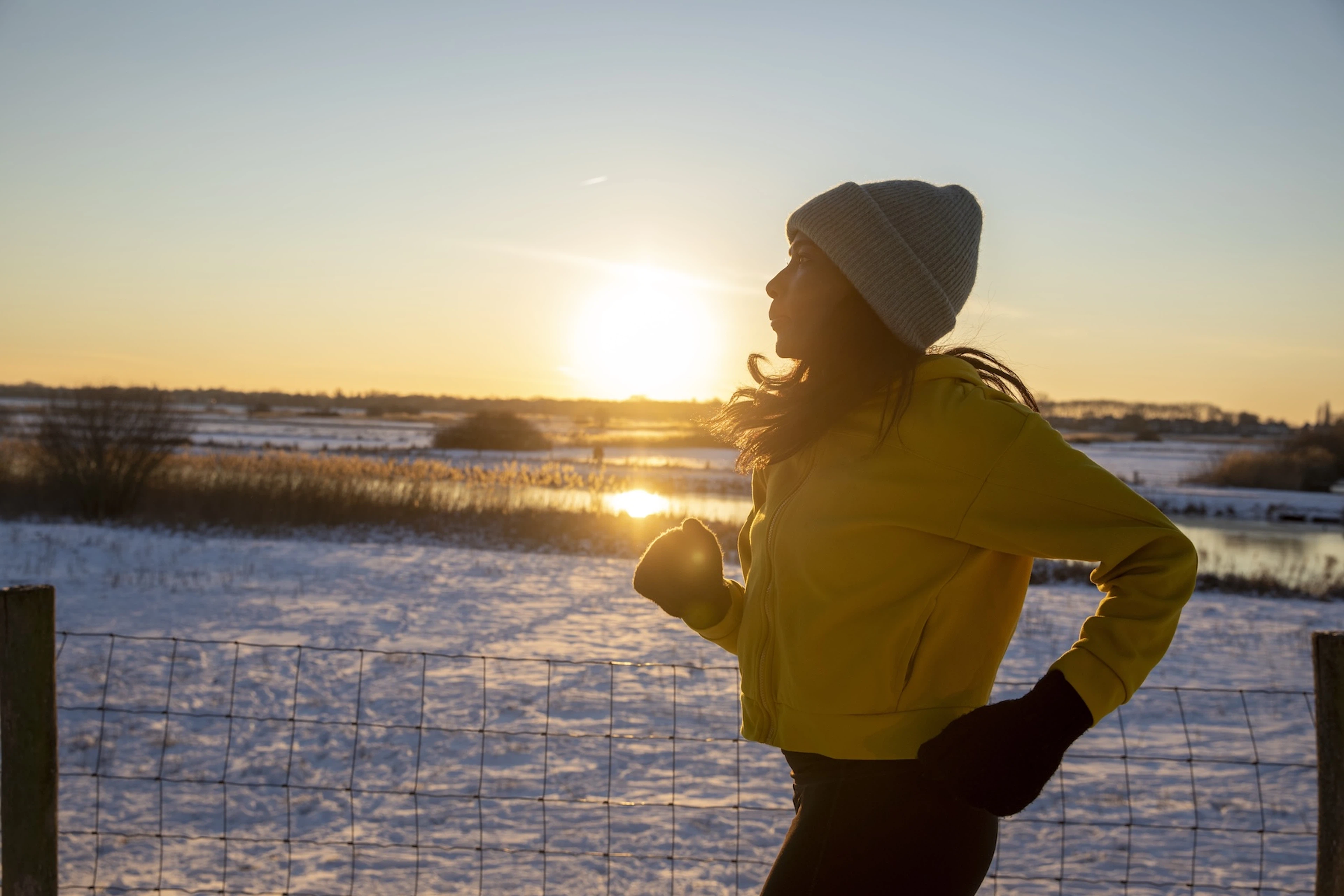 A woman exercising to ease seasonal affective disorder symptoms. She's going for a run in the early morning on a snowy day.