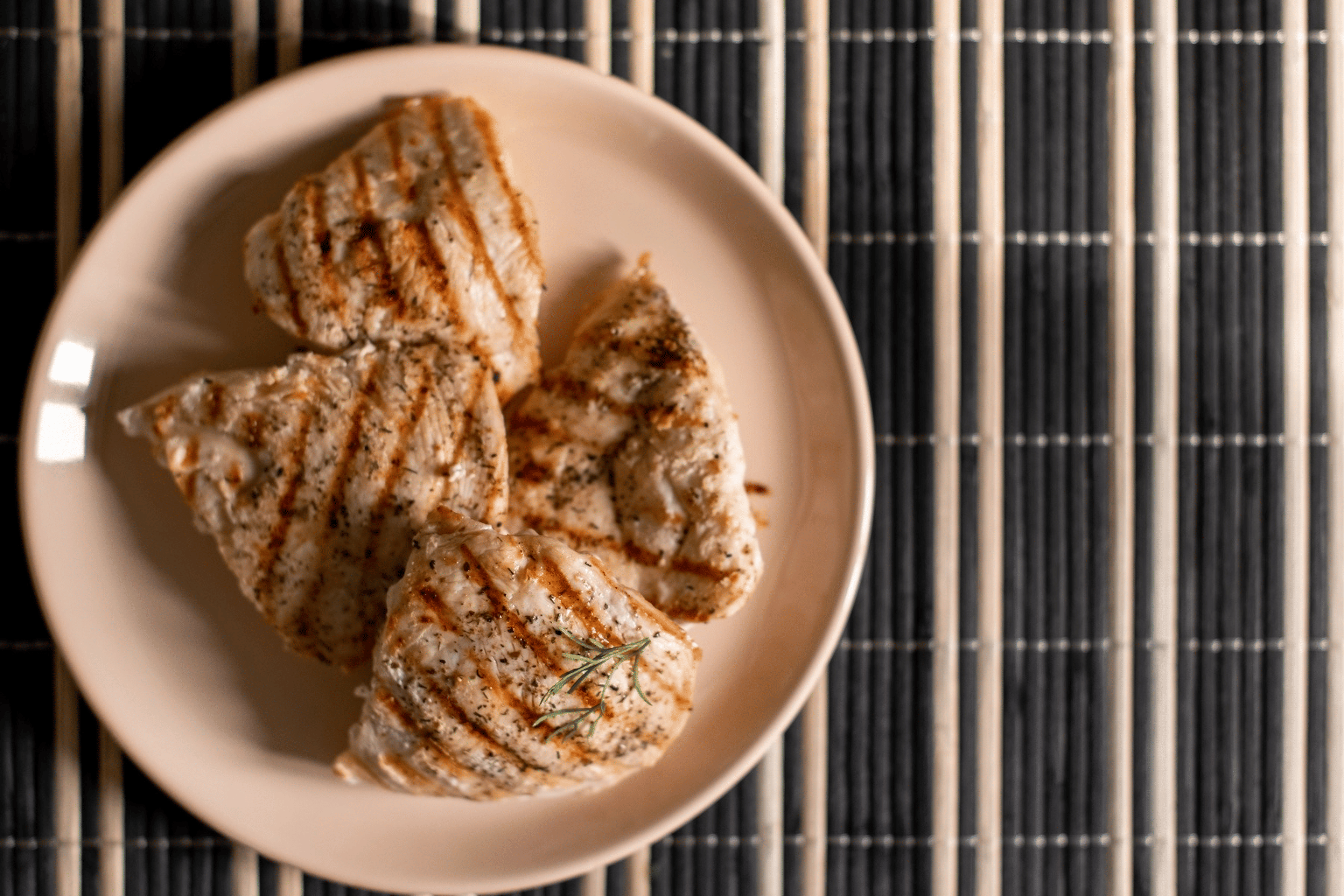 A plate of four grilled chicken breasts.