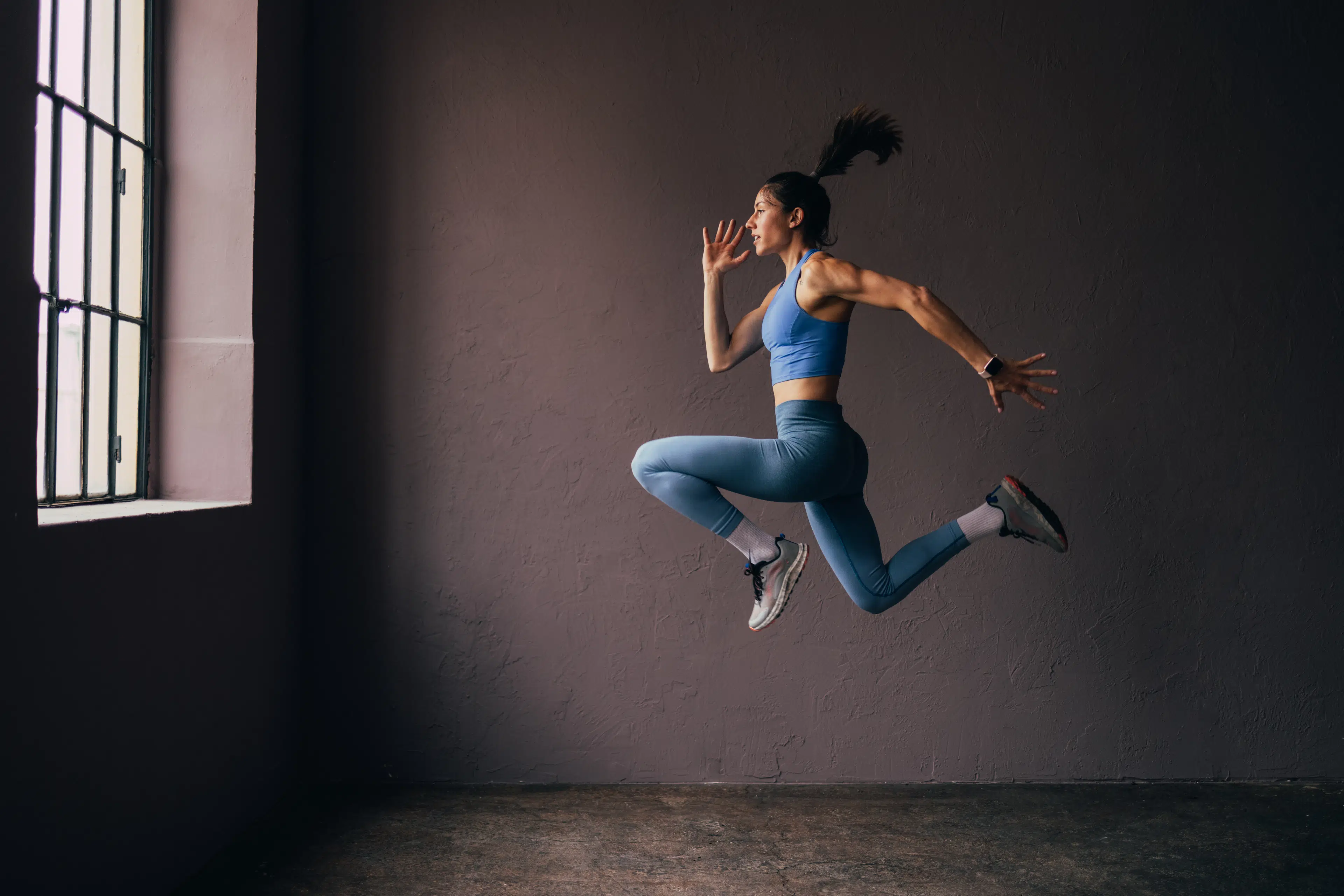 Woman does a jumping exercise indoors, an explosive exercise 