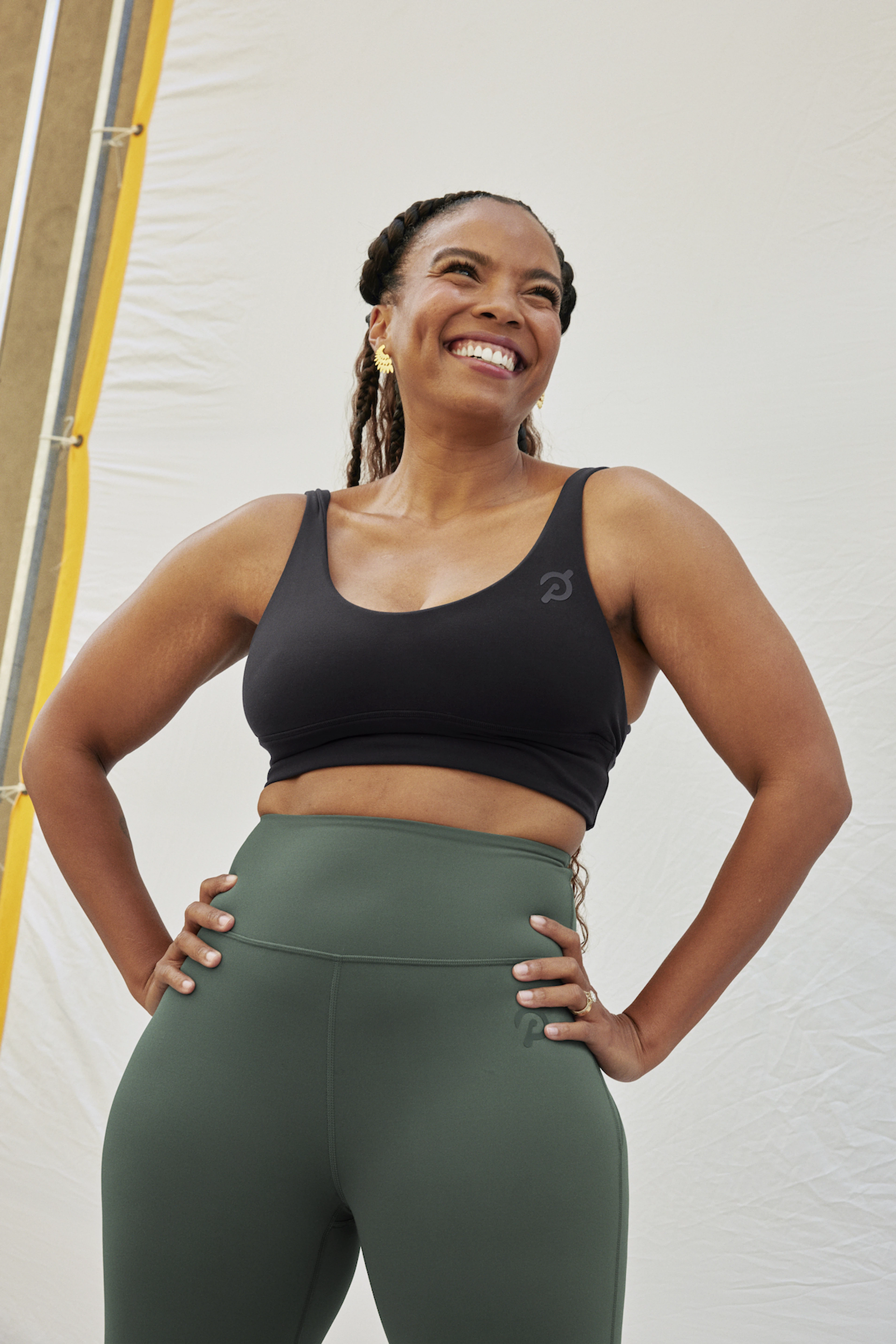 In this image for an article about how gym clothes affect motivation and performance, Peloton instructor Chelsea Jackson Roberts is grinning in a black sports bra and sage green leggings.