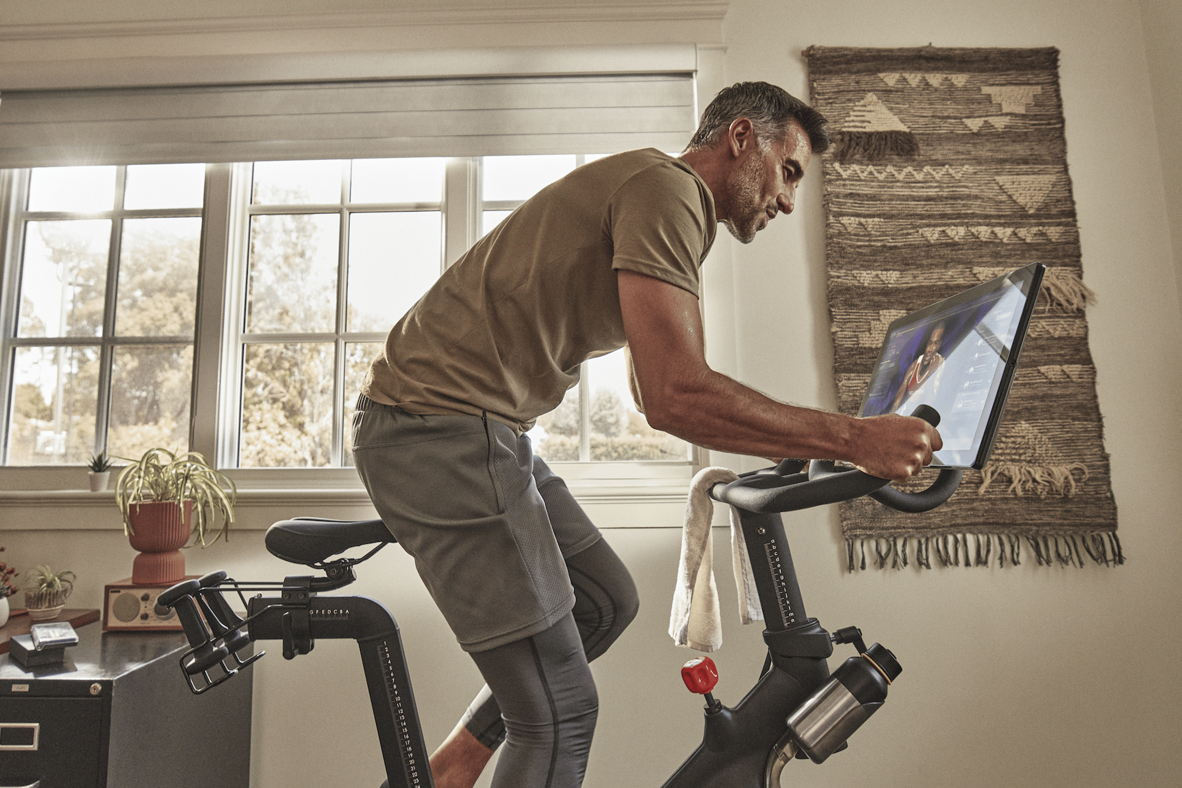 Man rides Peloton Bike at home.