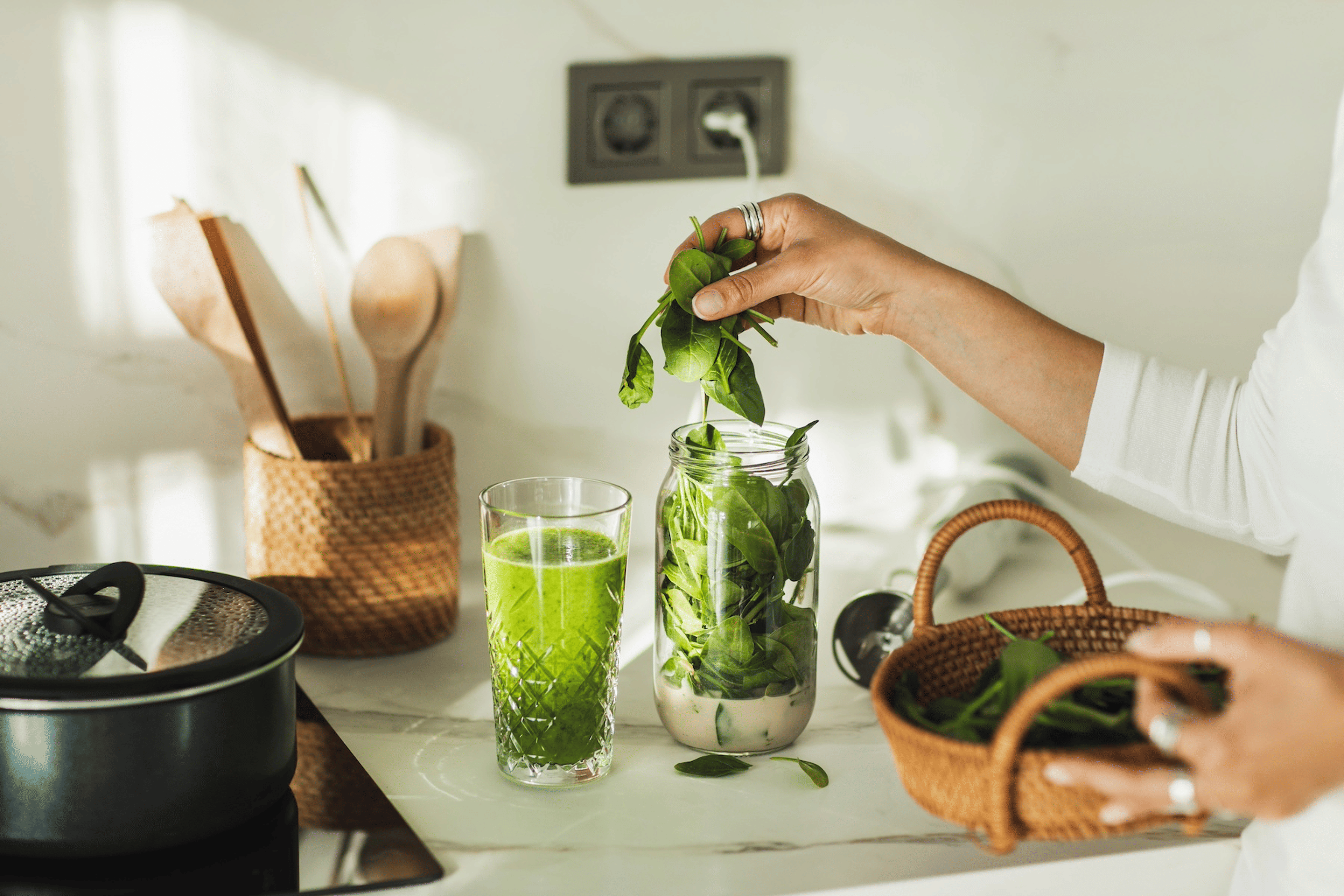 A woman putting spinach into a small blender cup. Spinach is a high-protein vegetable.