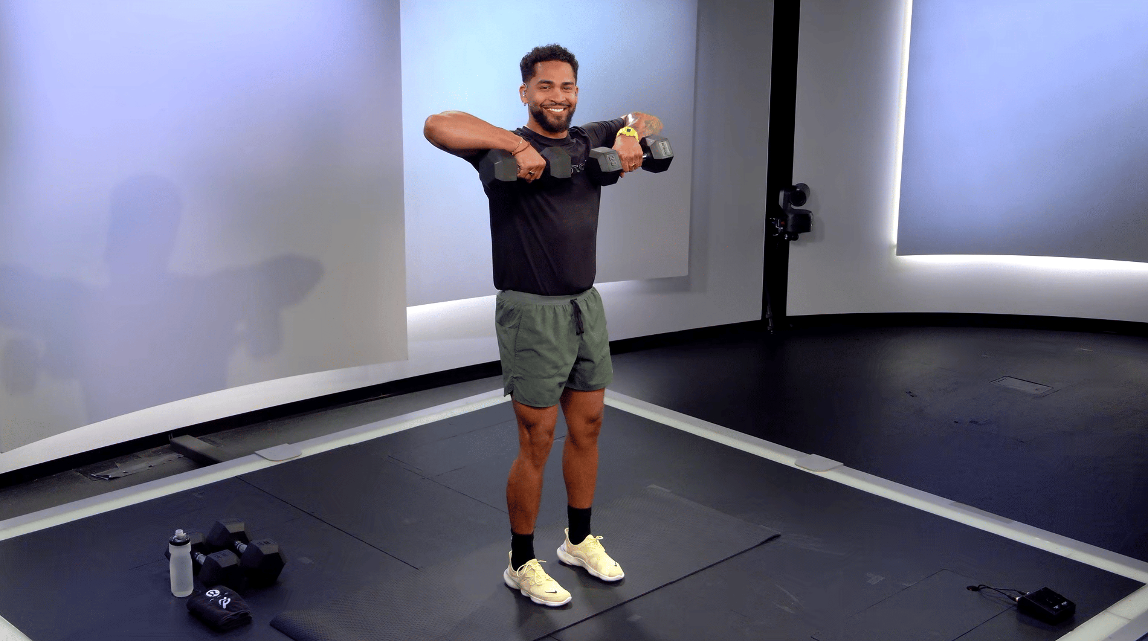 Peloton instructor Rad Lopez demonstrating a dumbbell upright row with proper form