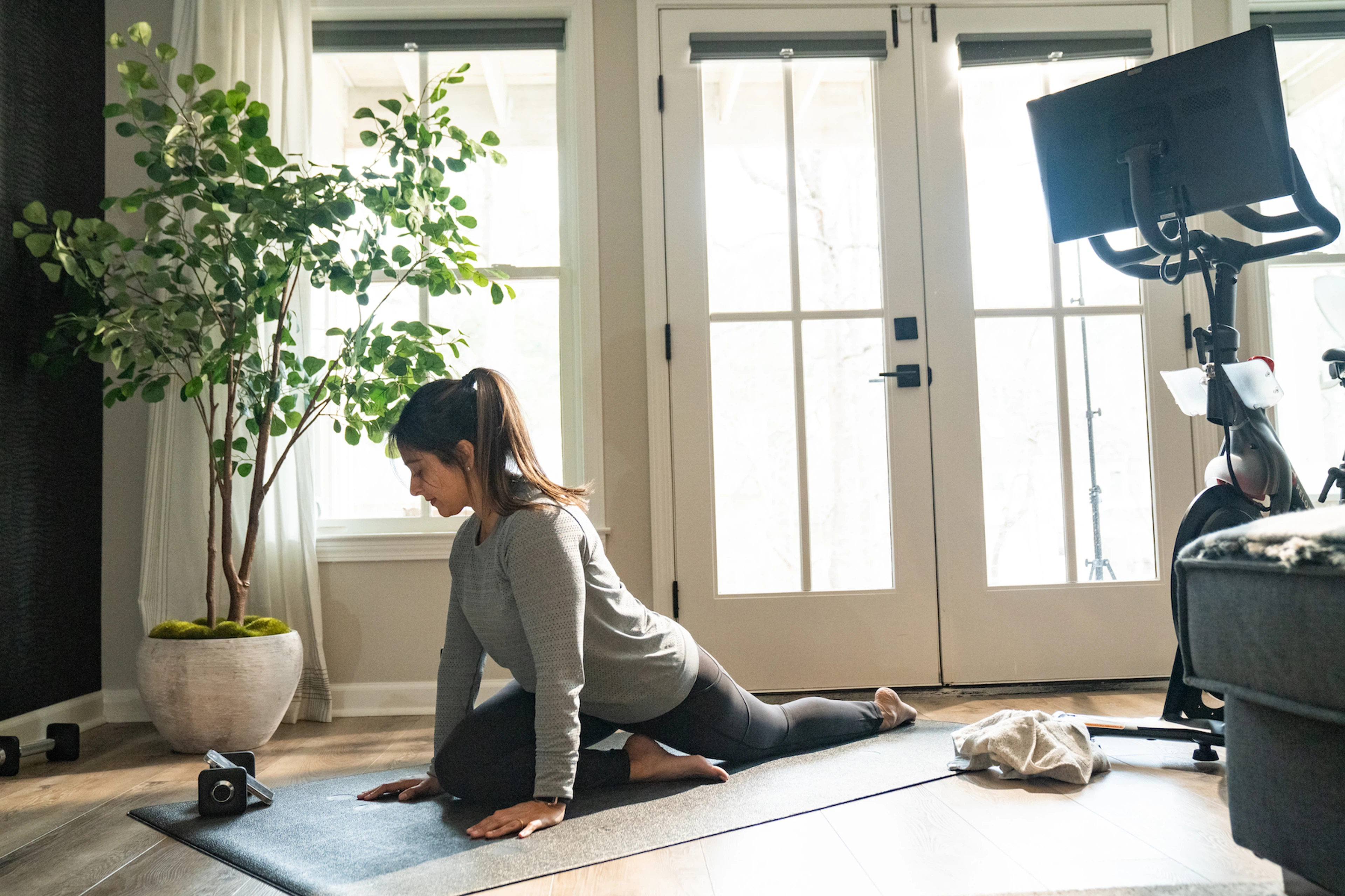Woman stretches at home while watching a video on phone