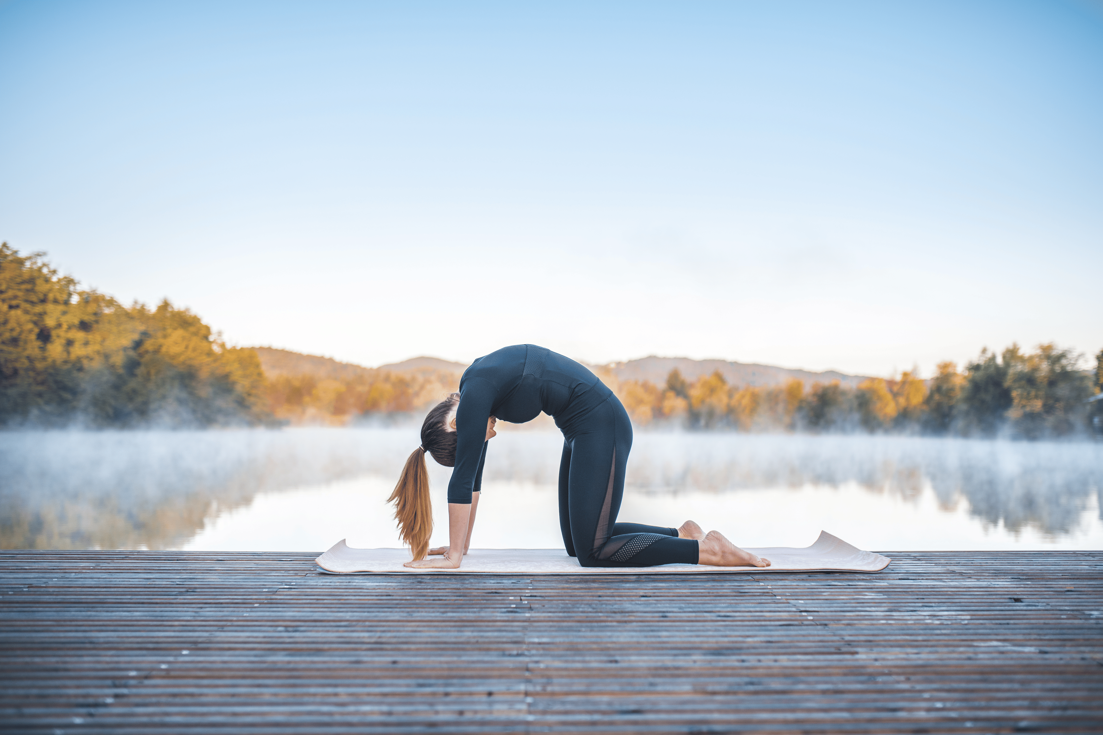 Woman practices Cat Cow yoga pose outdoors