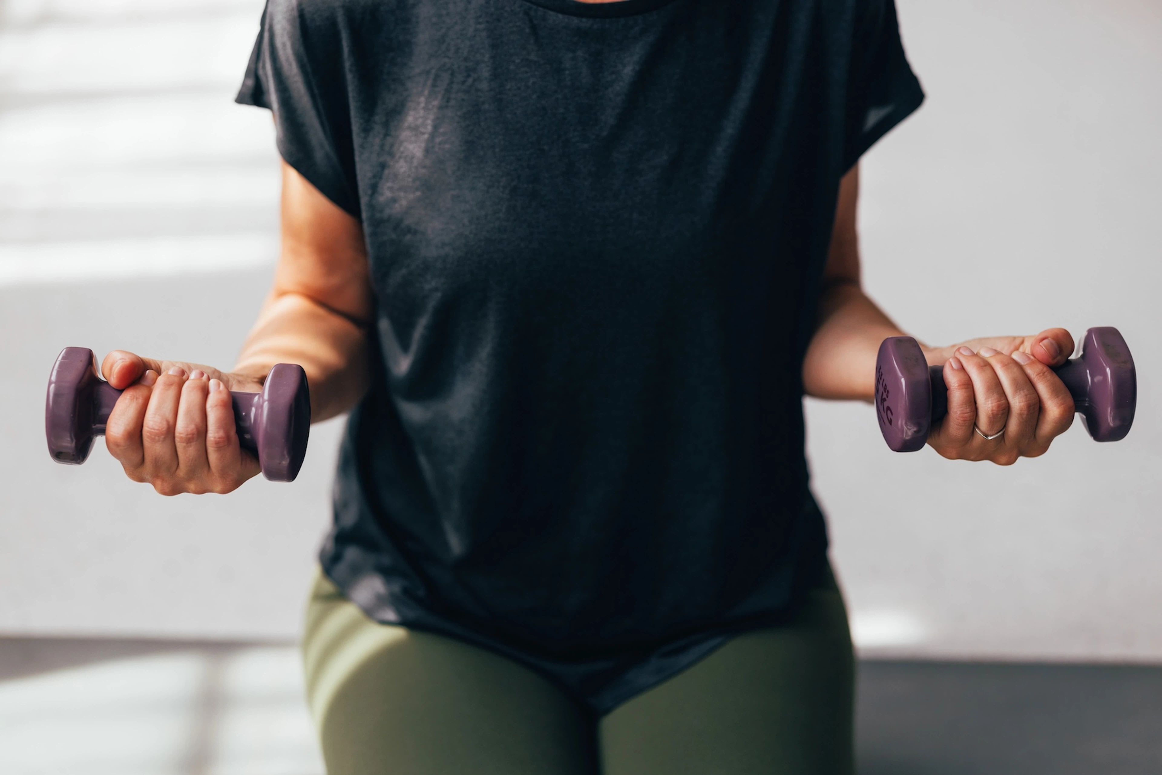 A close-up photo of someone doing a bicep curl with light weights. 